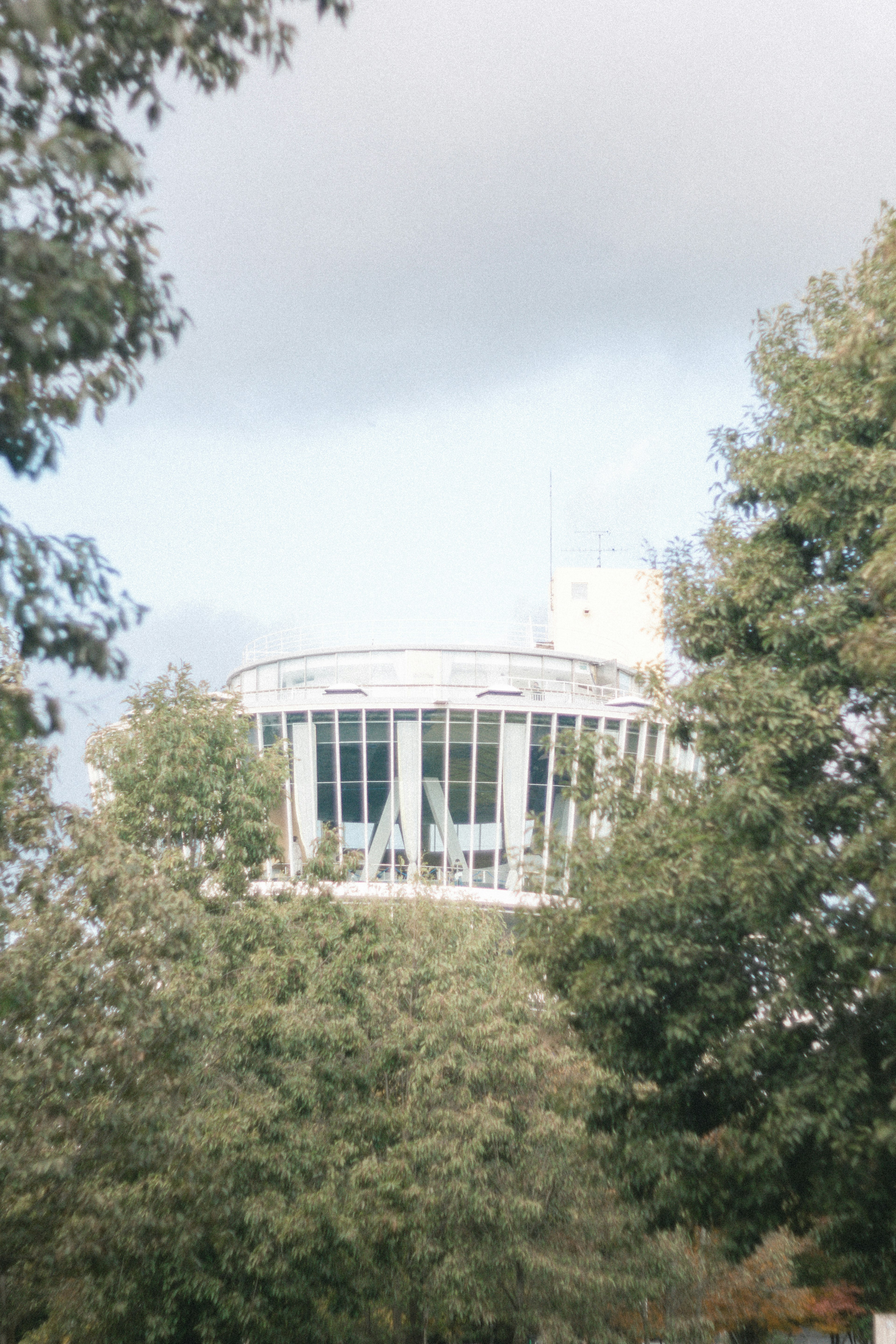 Ein modernes Gebäude, das teilweise von Bäumen in einer grünen Landschaft verdeckt ist