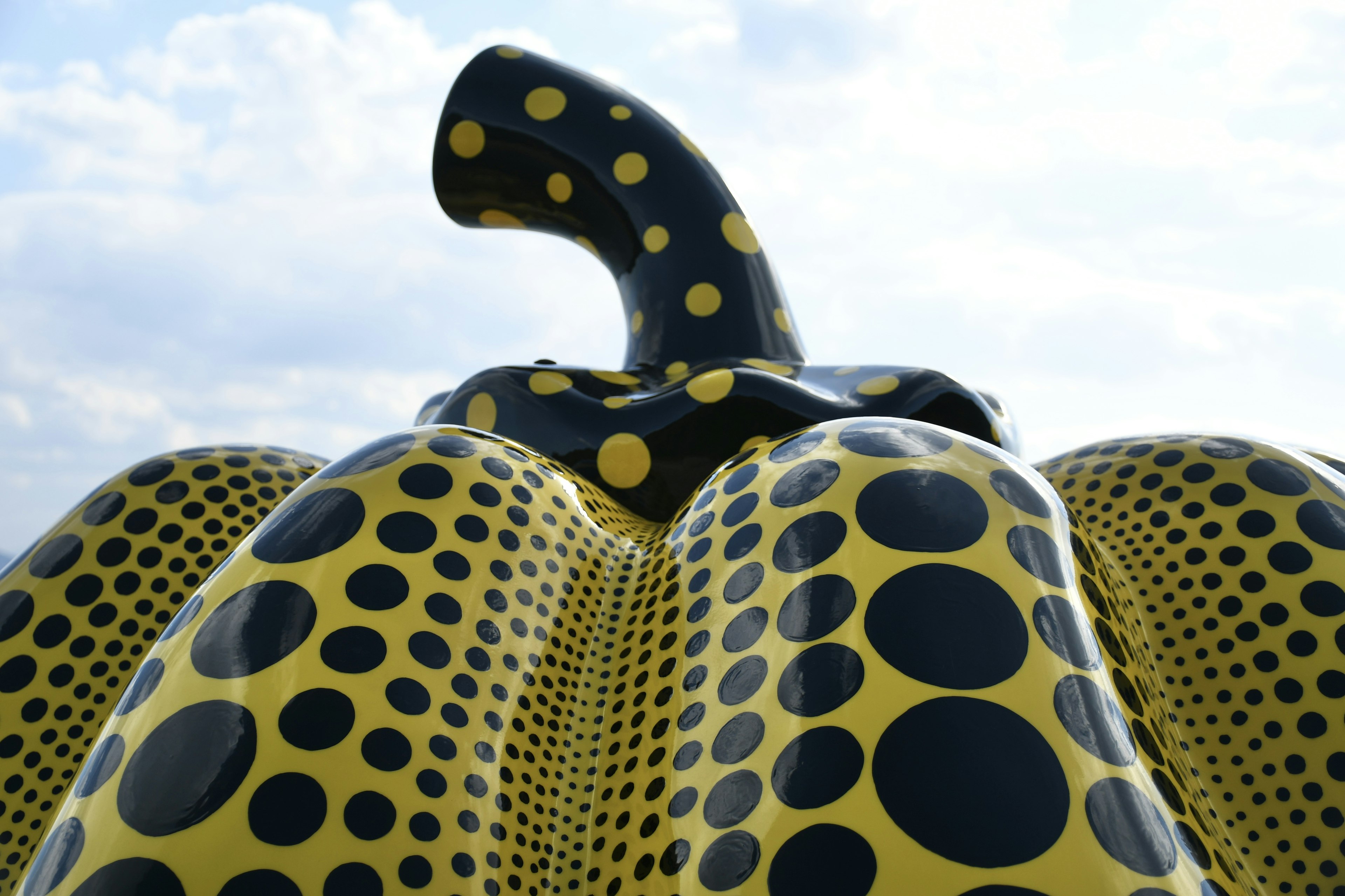 Scultura di zucca gialla con pois neri che si erge verso il cielo