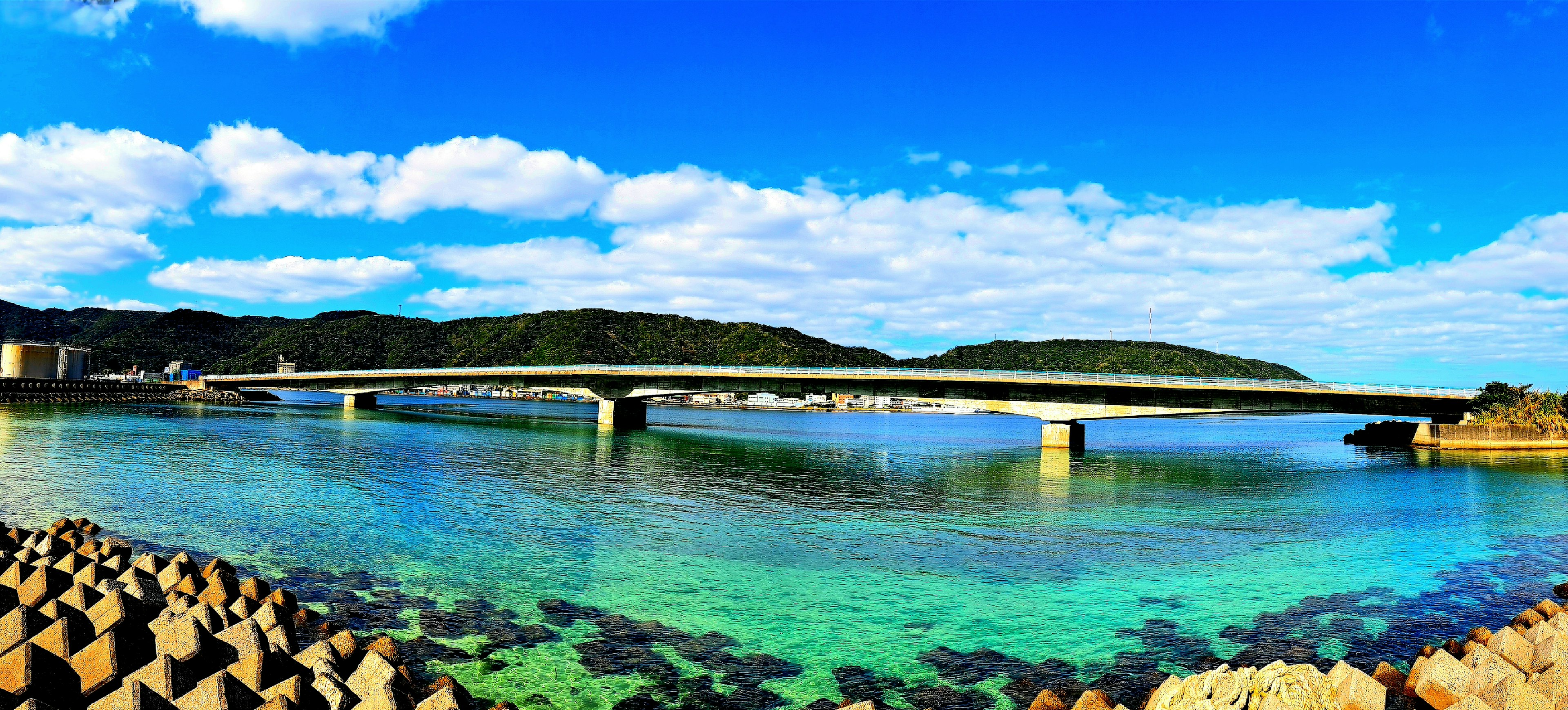 Pemandangan jembatan di atas air turquoise yang jernih di bawah langit biru