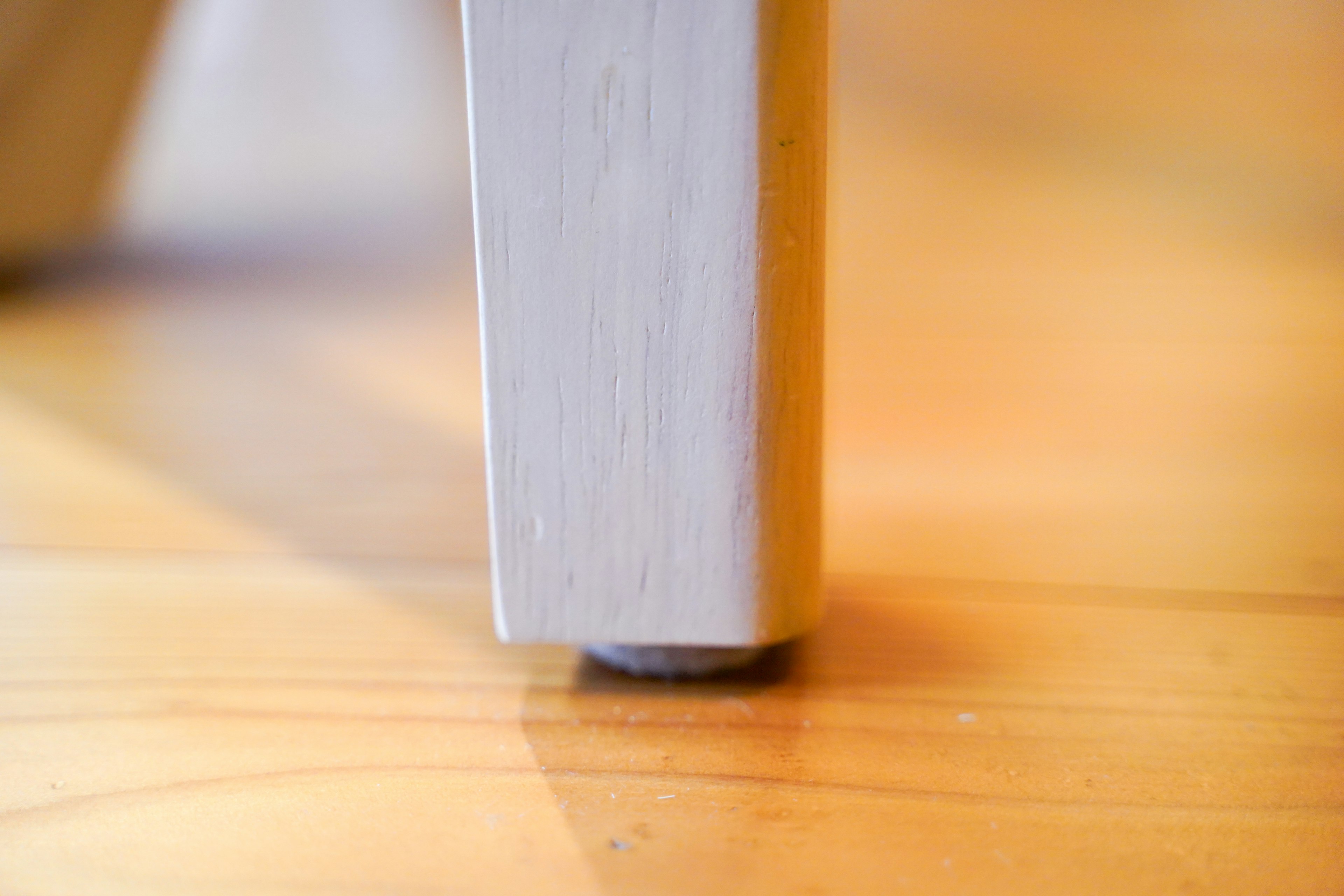 Close-up of a white chair leg making contact with the floor