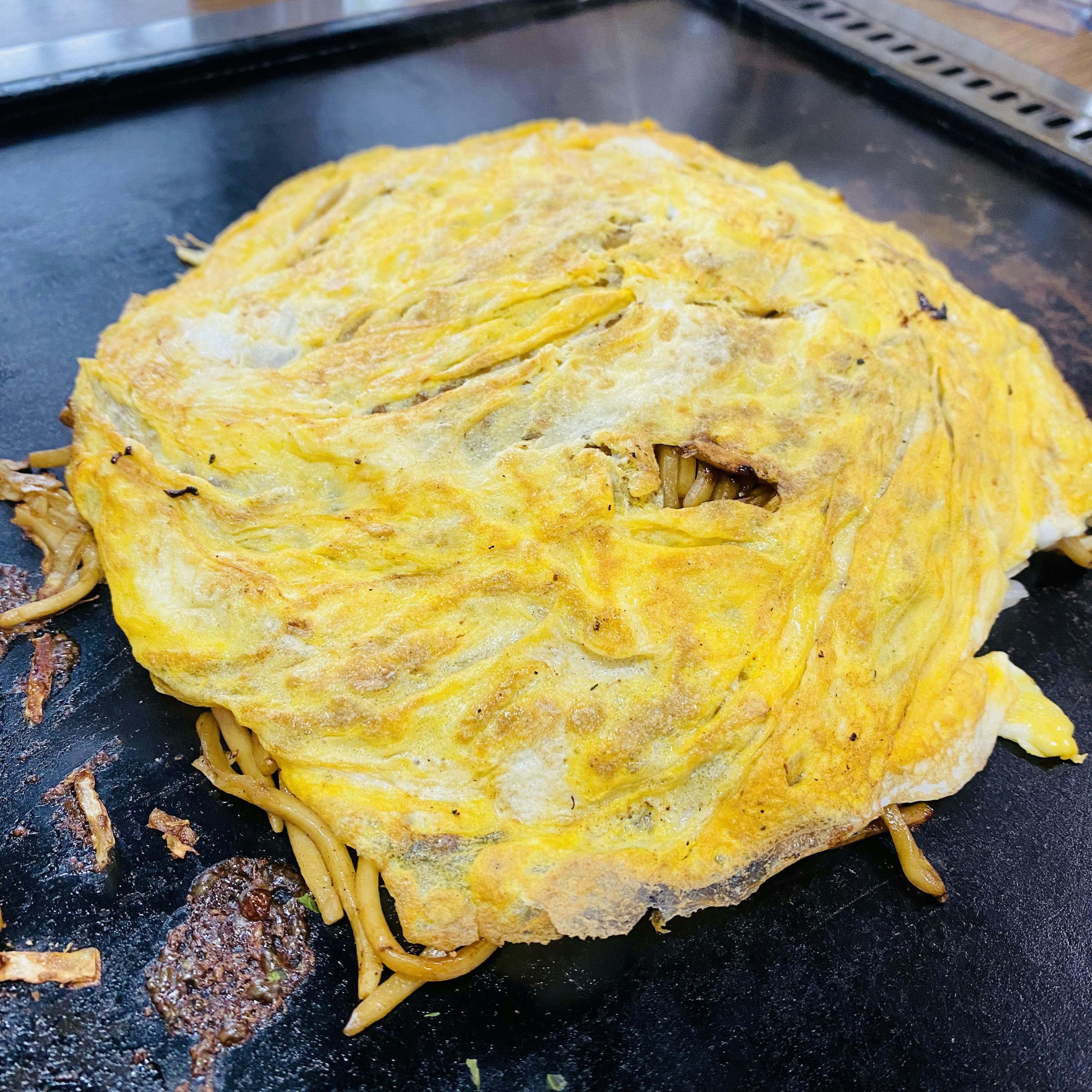 Noodles saltati avvolti in un'omelette su una piastra