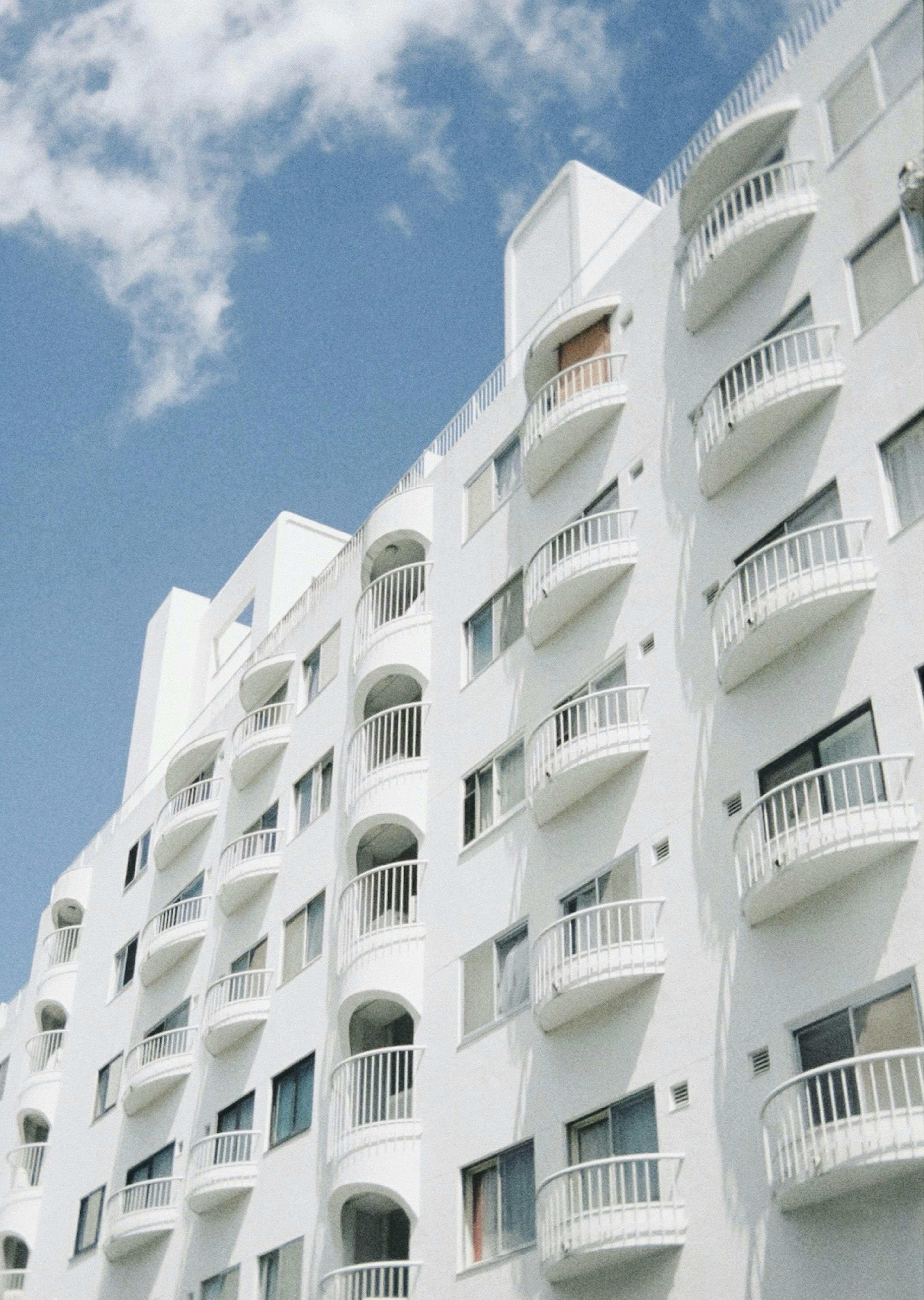 Exterior of a white apartment building under a blue sky featuring distinctive balconies