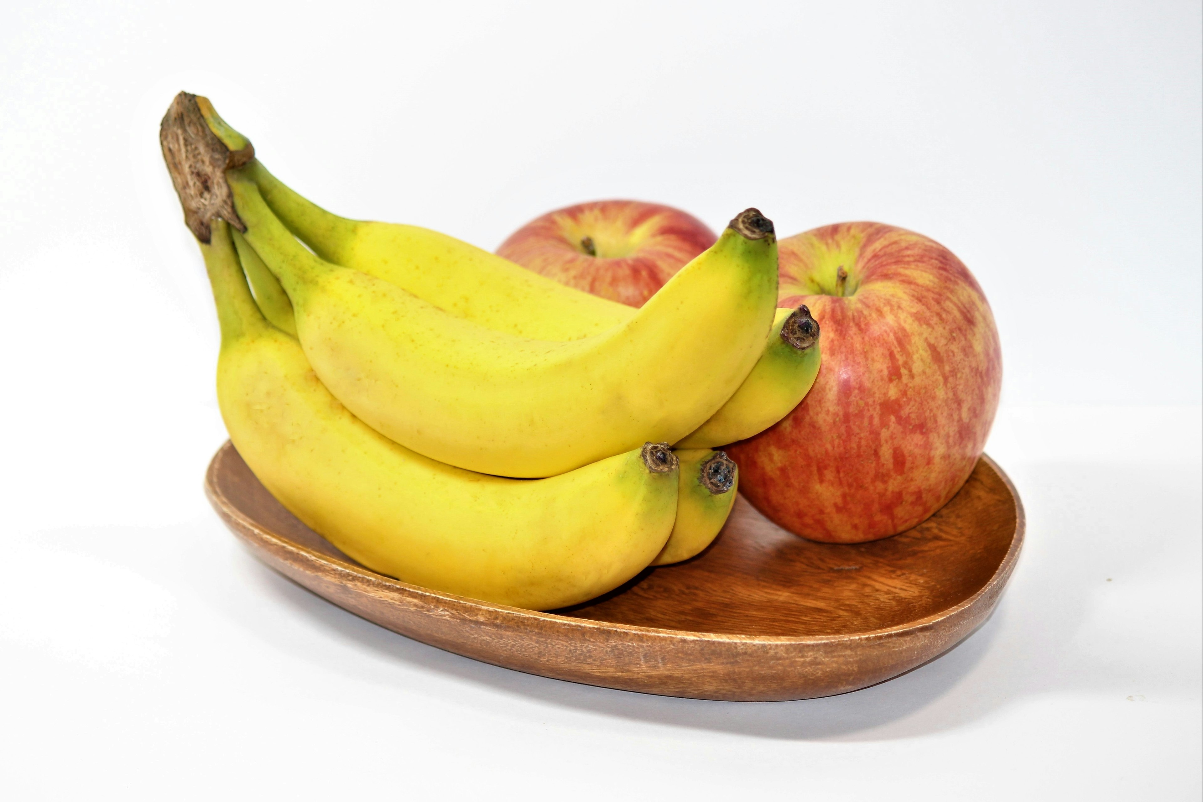 Composizione di frutta con banane e mele su un piatto di legno