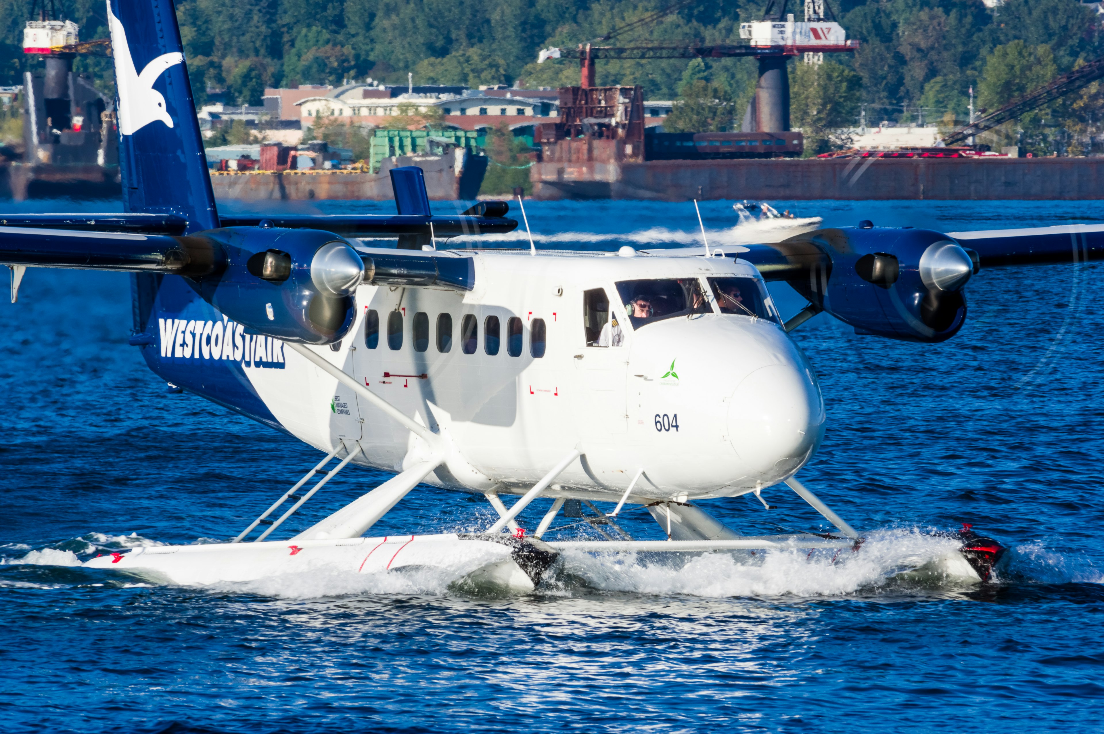 Idrovolante Cessna che atterra sull'acqua con un porto sullo sfondo