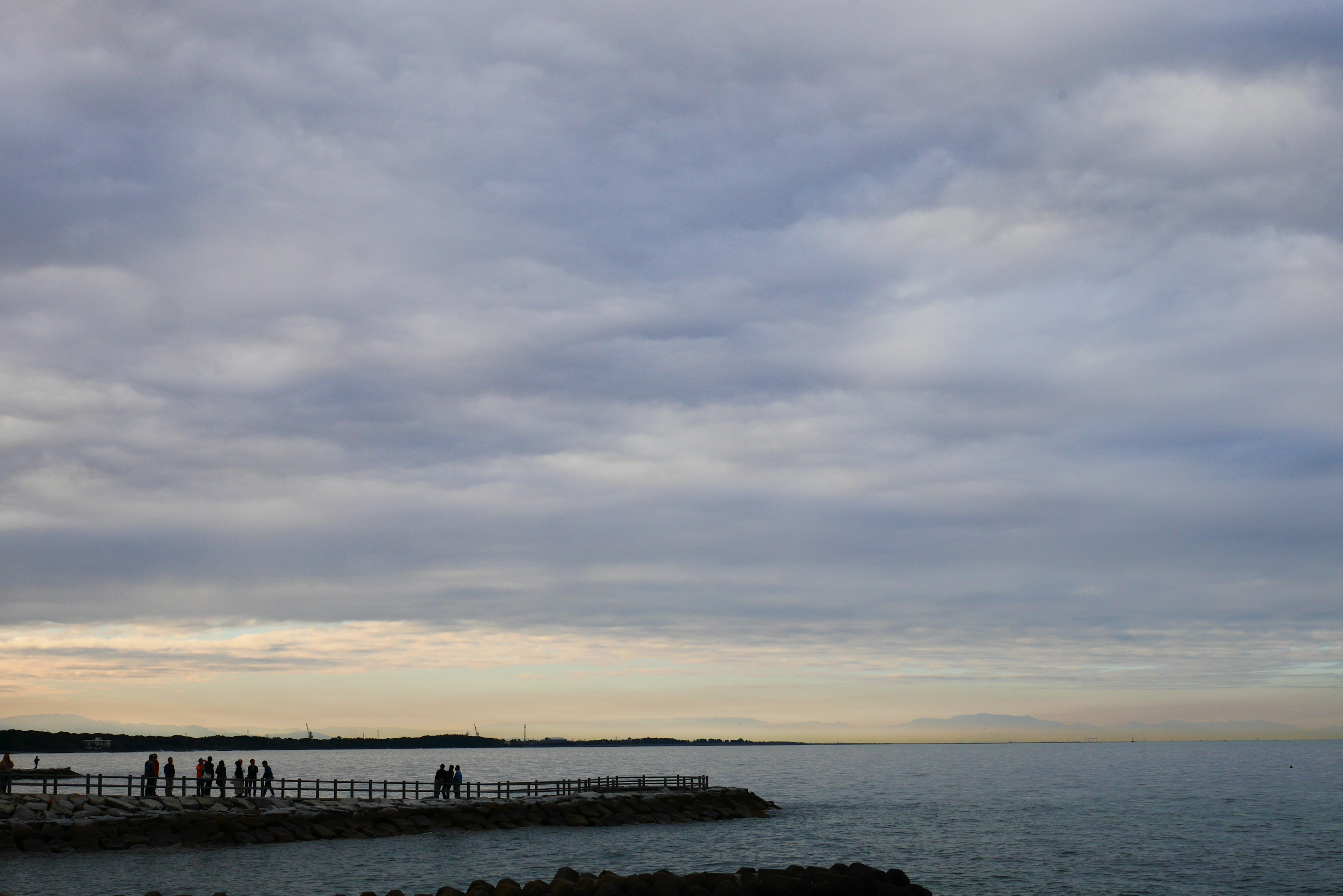 人們站在海邊，海洋藍色，天空多雲