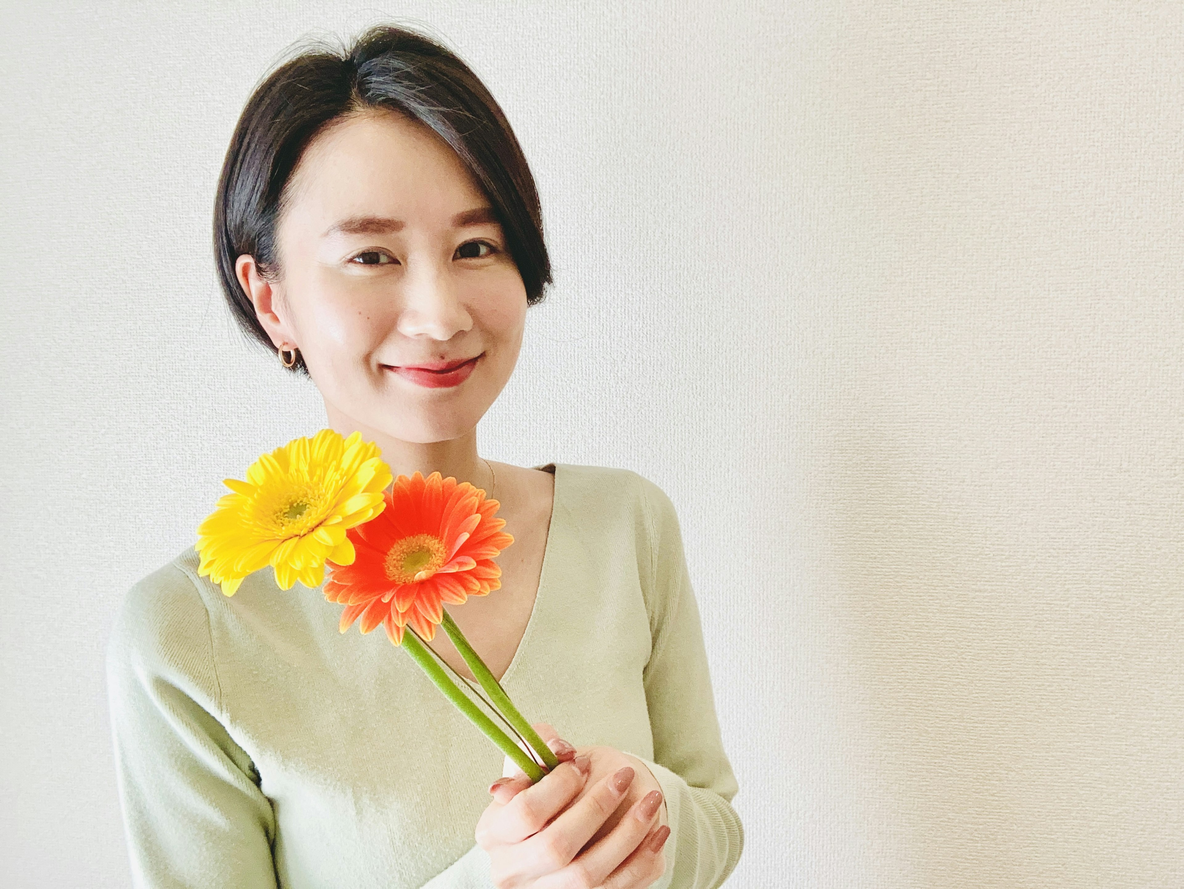 Retrato de una mujer sosteniendo flores flores de colores brillantes con un fondo suave