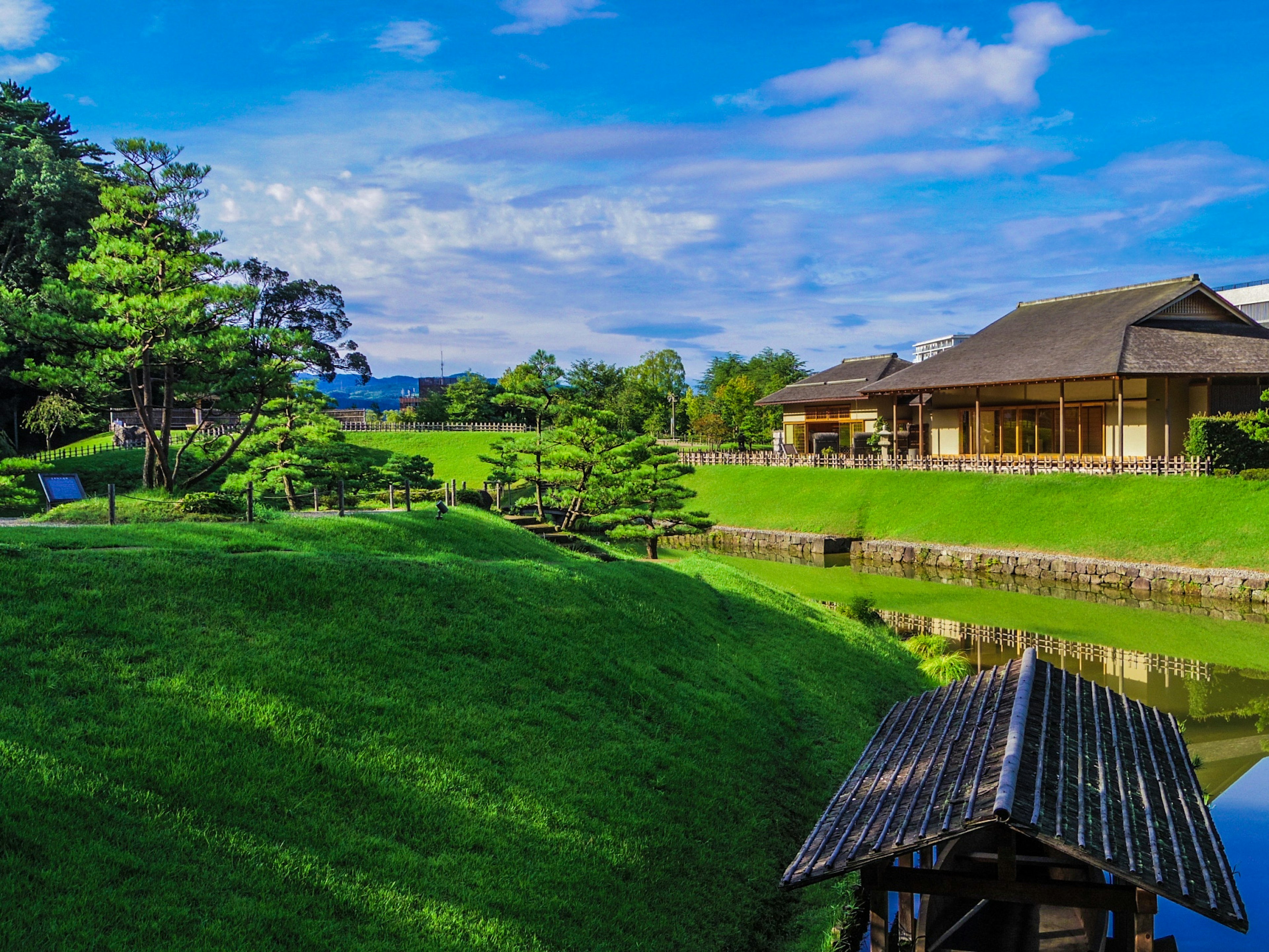 Vista escénica de un jardín japonés con colinas verdes y un estanque