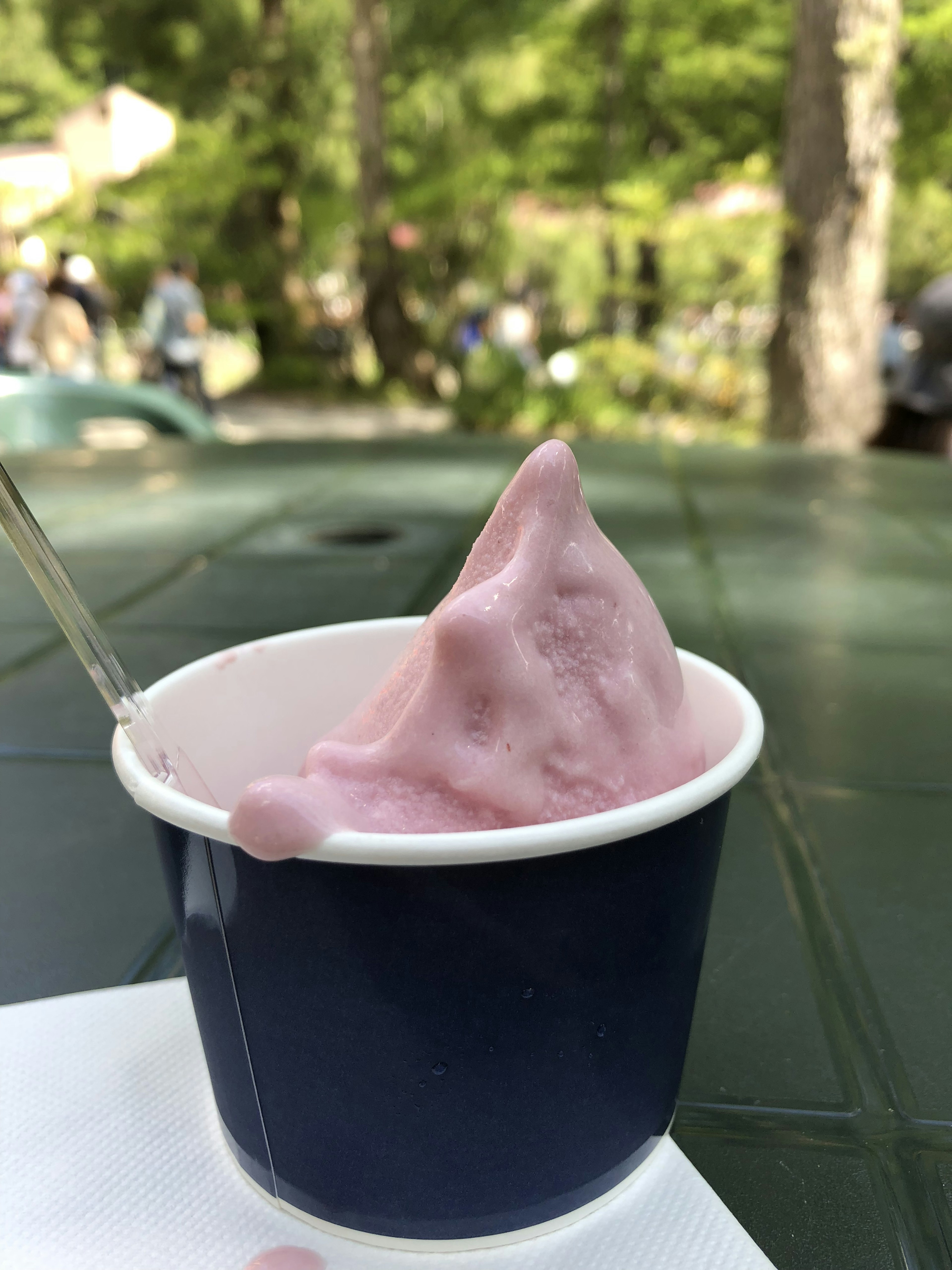 Un gelato morbido rosa in una tazza blu con alberi sullo sfondo