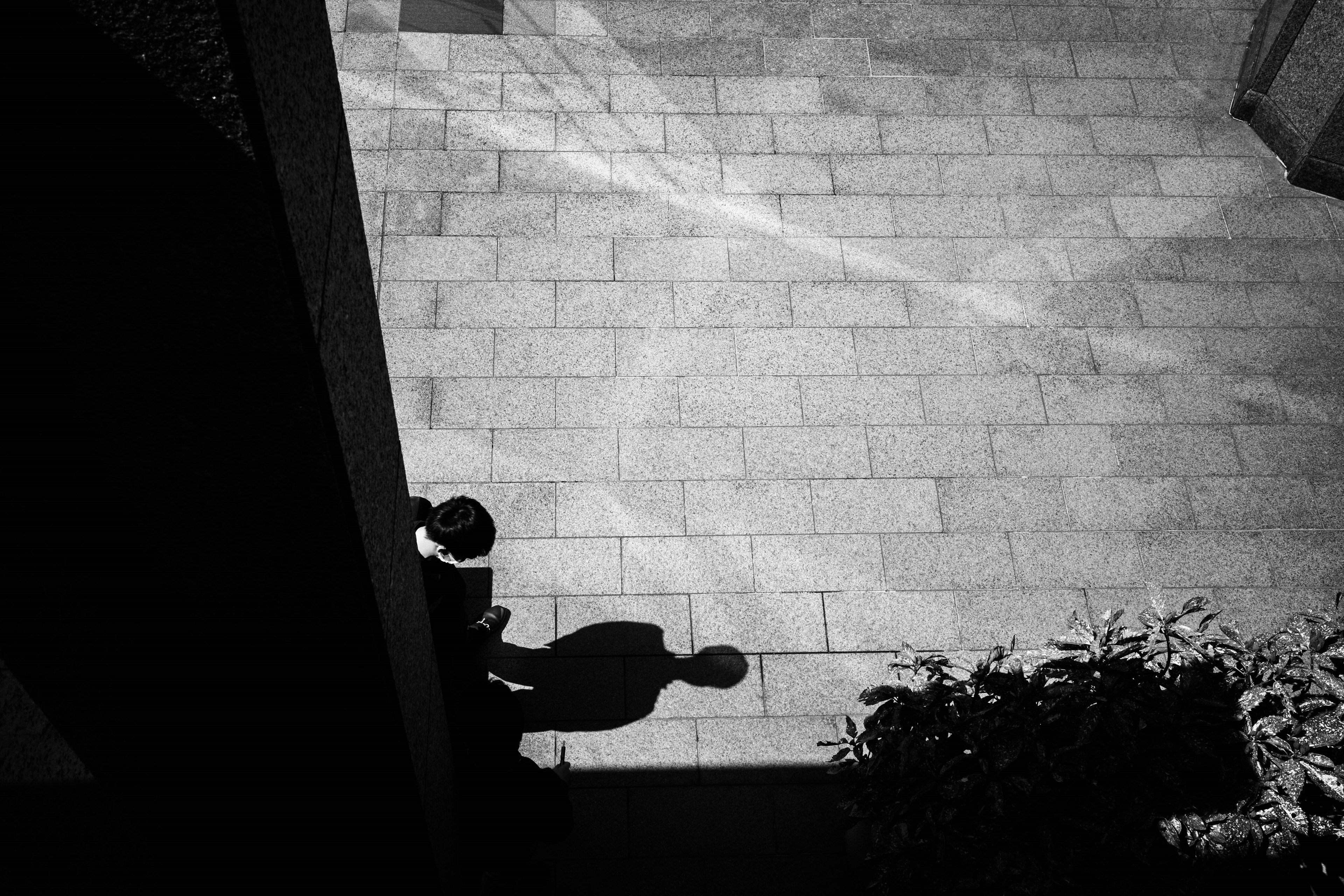 A shadow of a person standing in a quiet space highlighted by strong black and white contrast