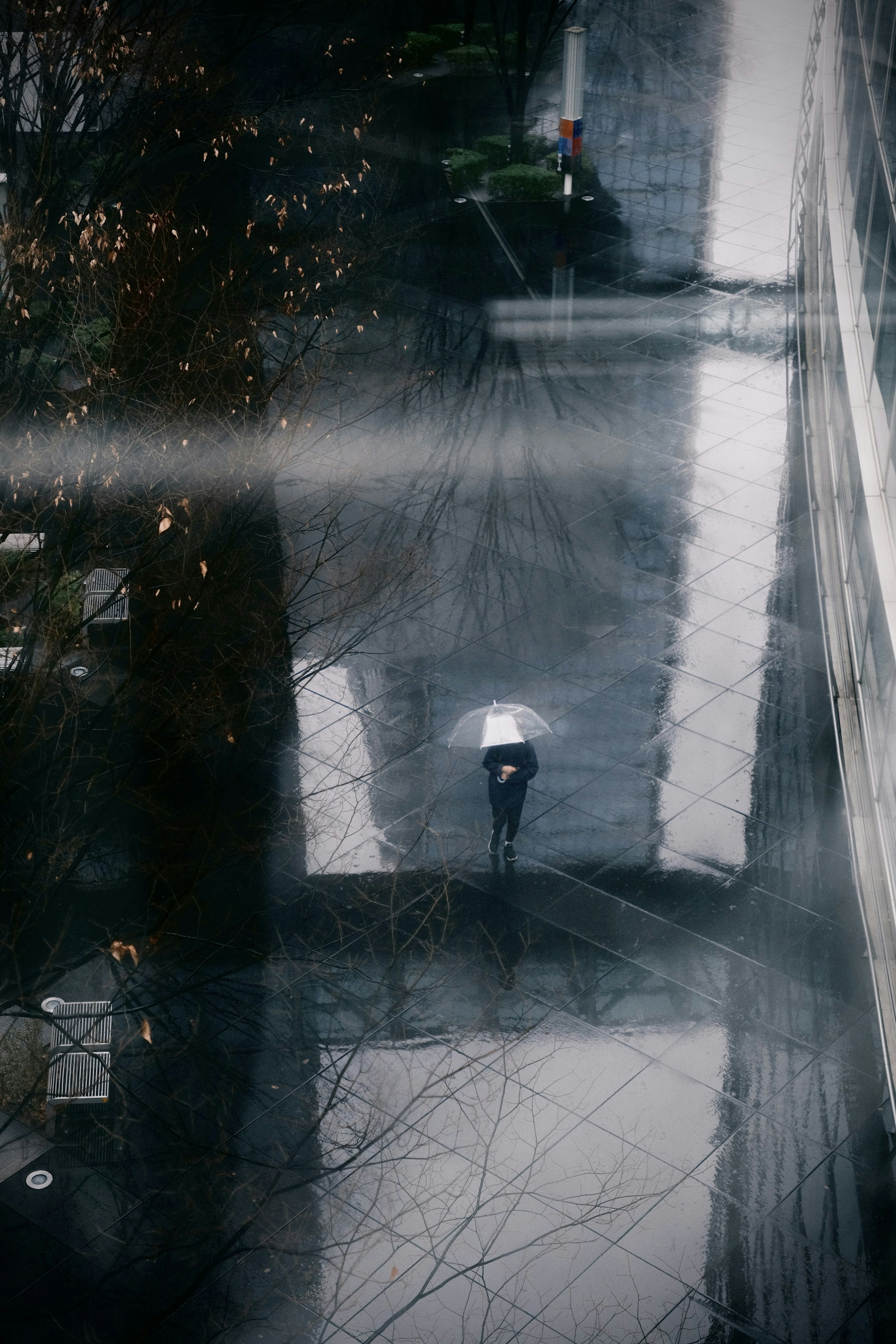 A person walking on a wet surface with an umbrella on a rainy day