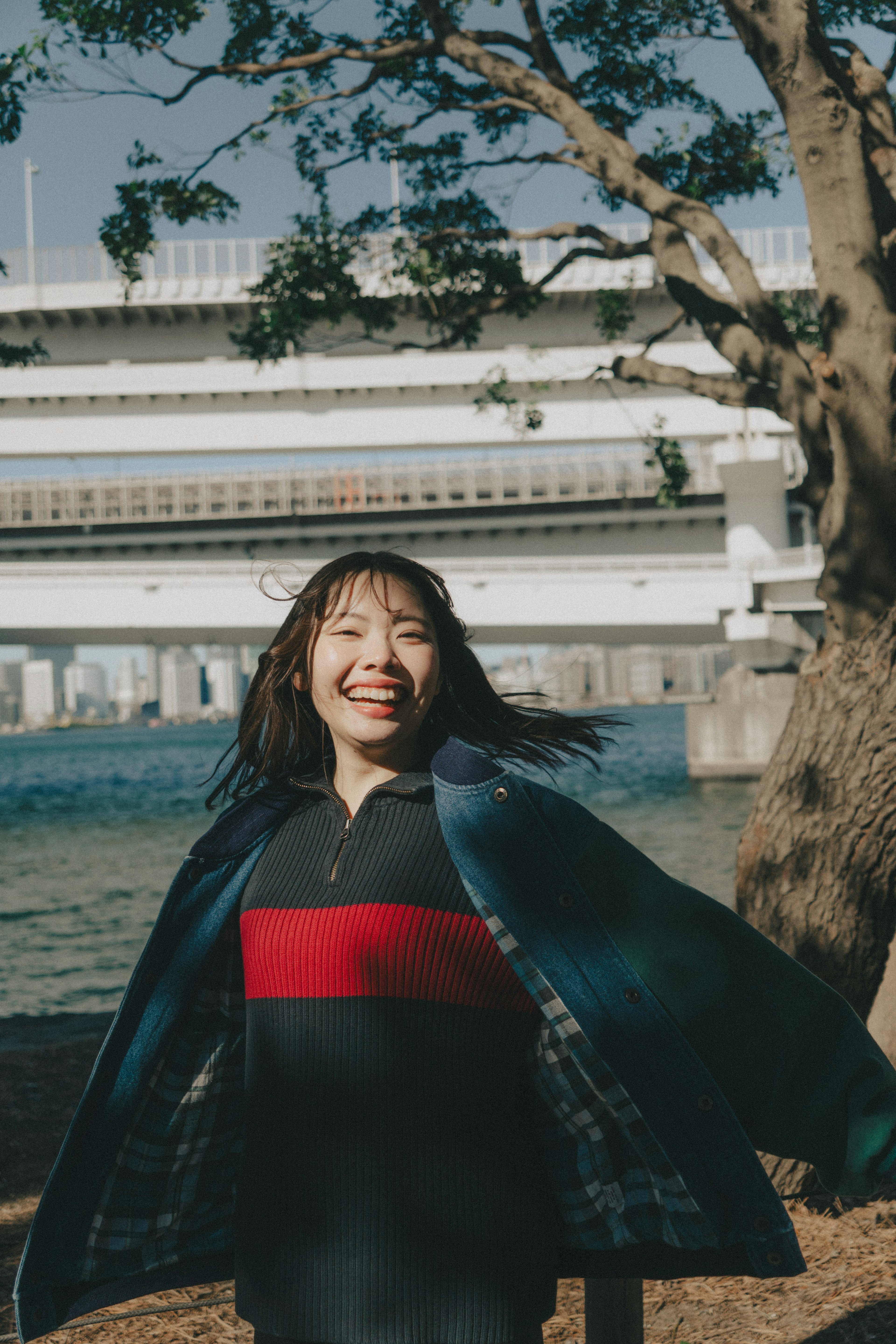 Mujer sonriente con abrigo debajo de un puente