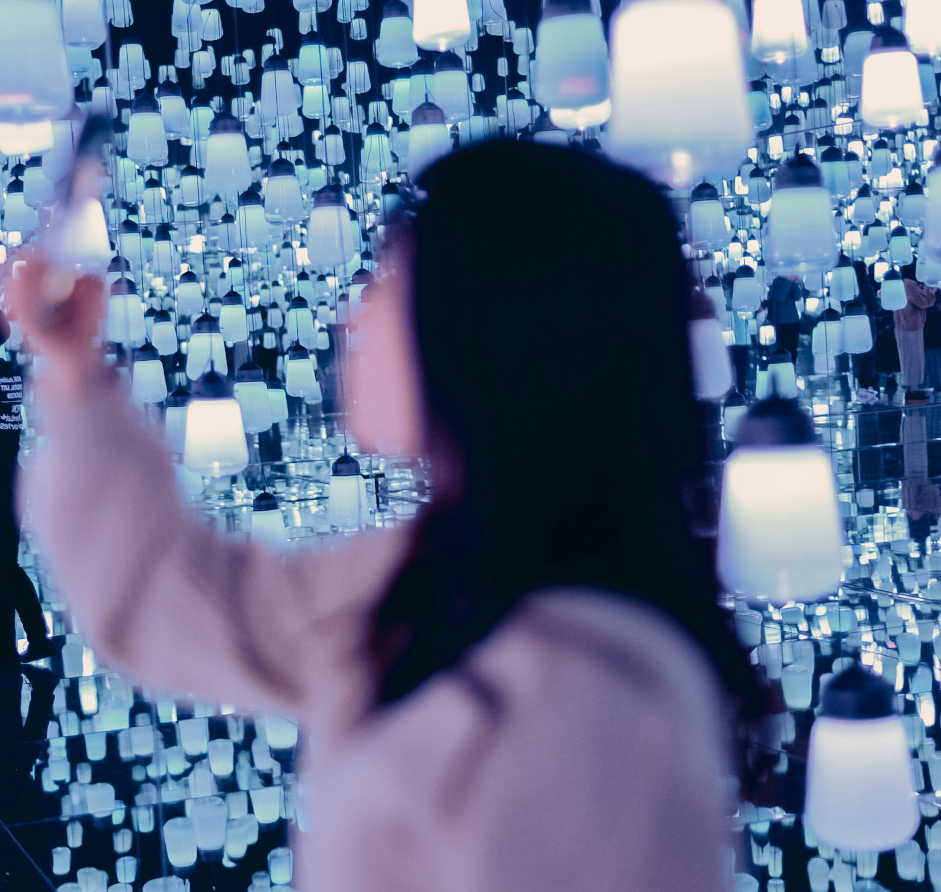 Une femme tenant un smartphone devant de nombreuses lampes éclairées en bleu