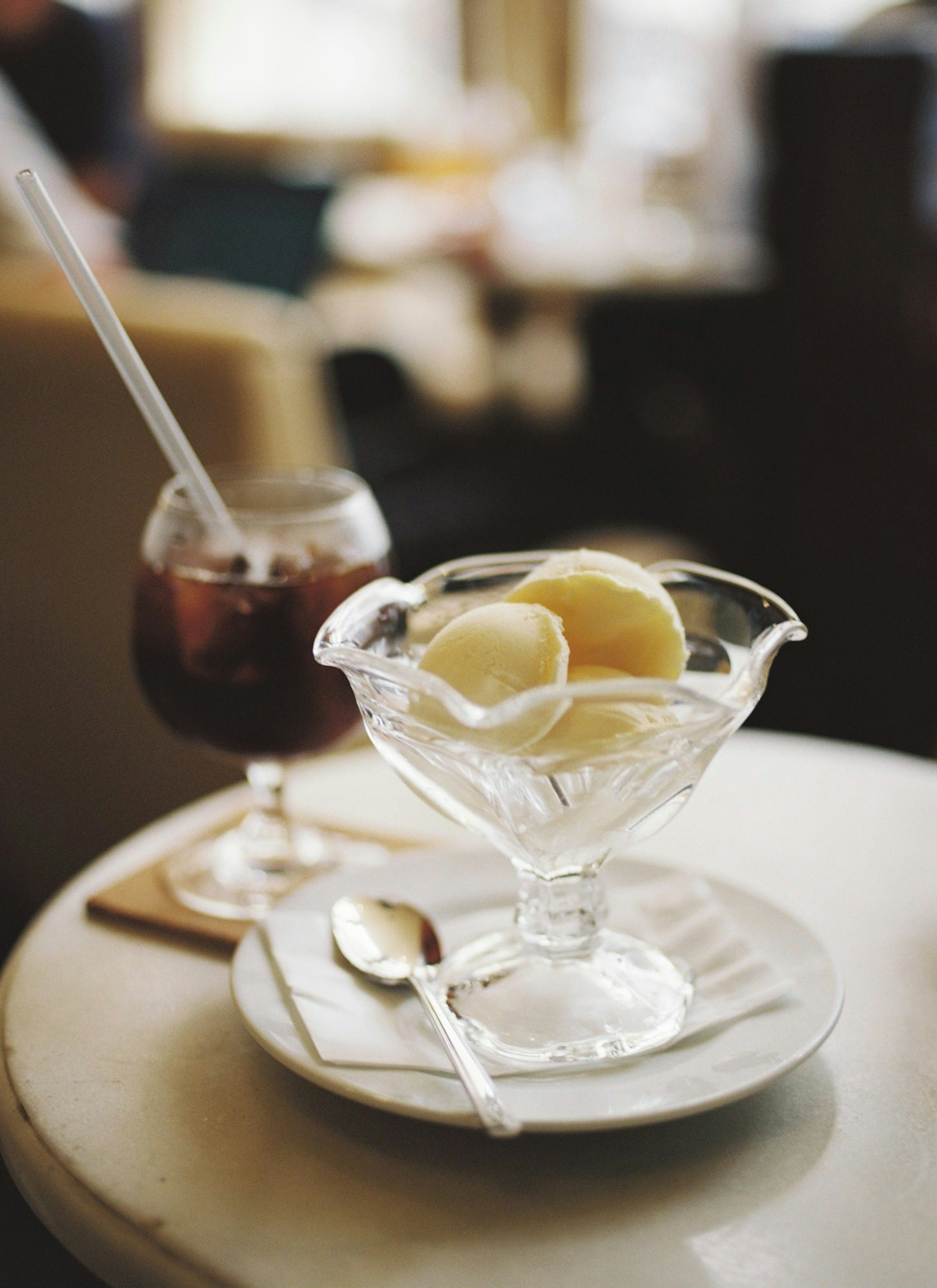 A cafe scene featuring a glass of ice cream and a drink on a table