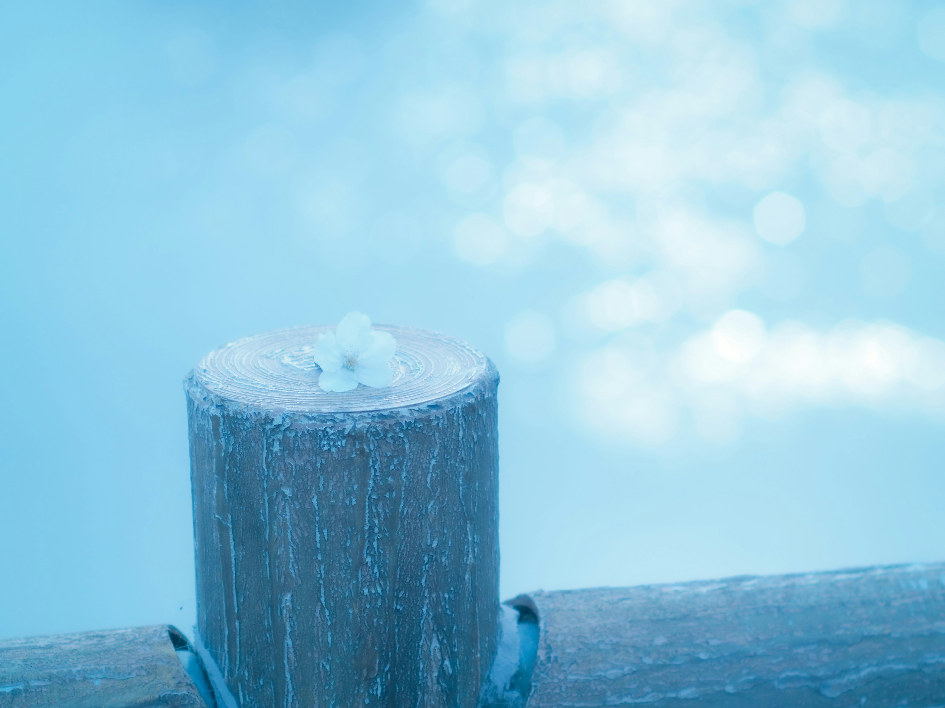 Holzpfahl mit schneeähnlicher Substanz vor blauem Hintergrund