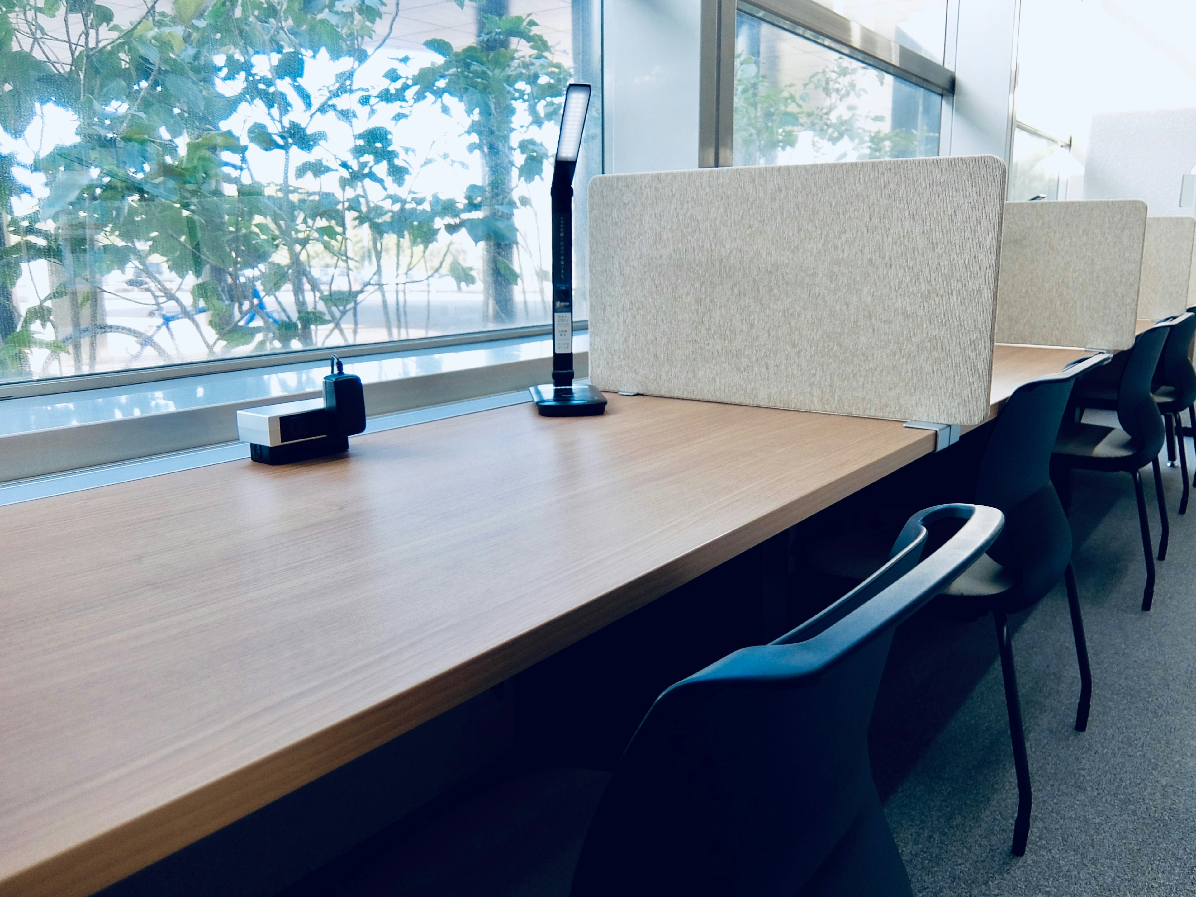 Espacio de trabajo brillante con mesa de madera y sillas negras luz natural que entra por la ventana