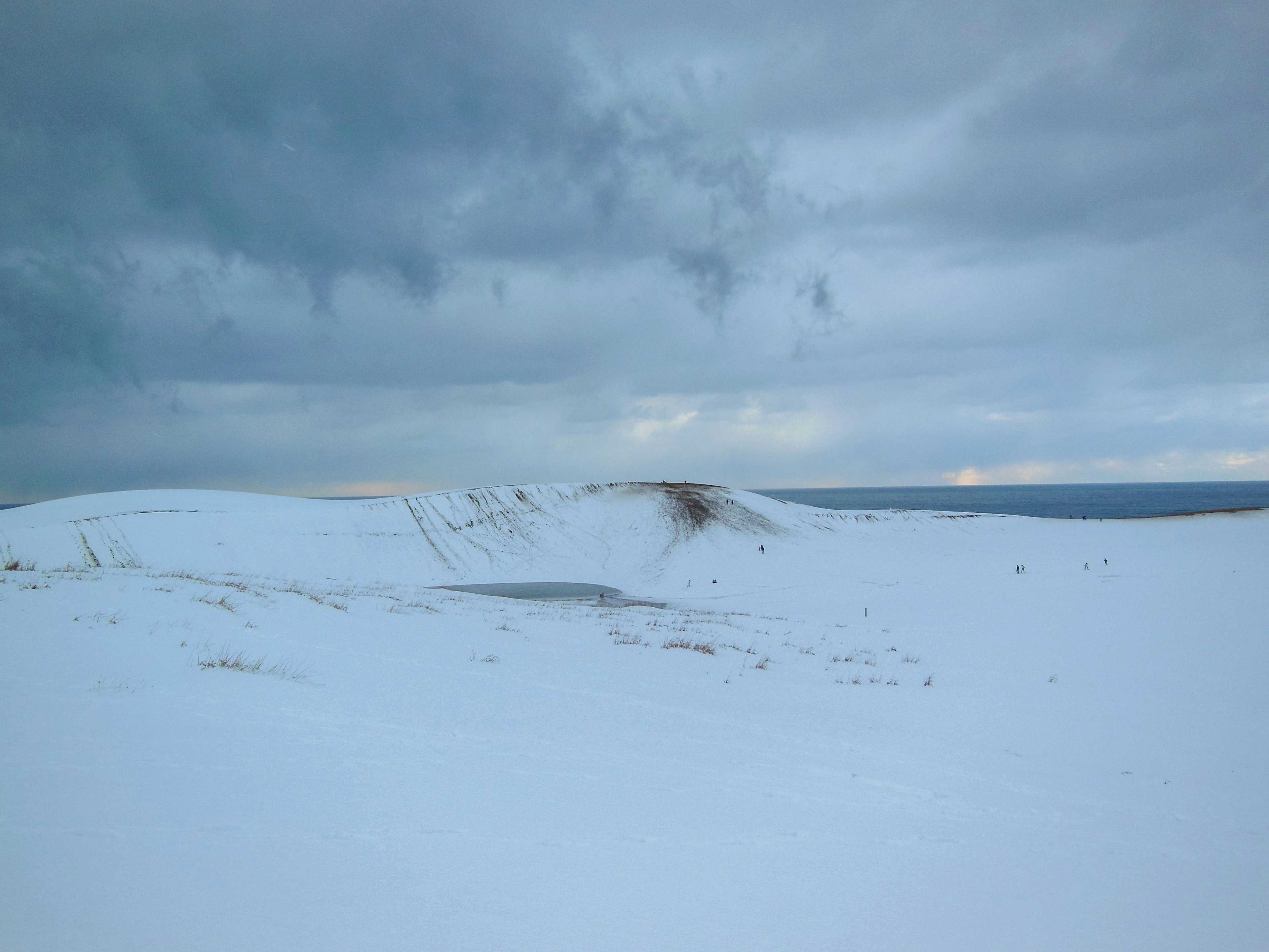 Weite verschneite Landschaft mit dunklen Wolken darüber