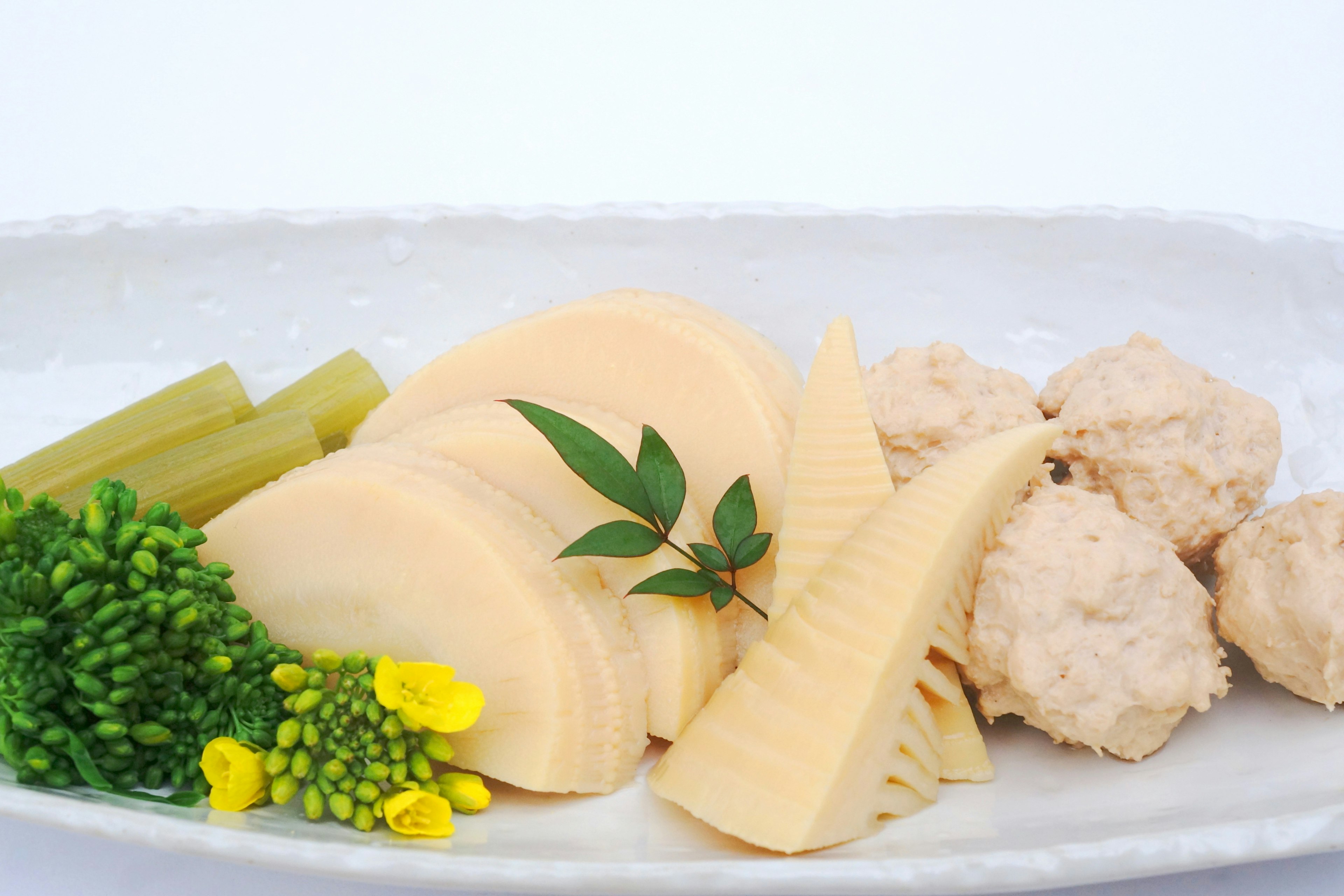 白い皿に盛られた竹の子と鶏肉の料理 彩り豊かな野菜とハーブが添えられている