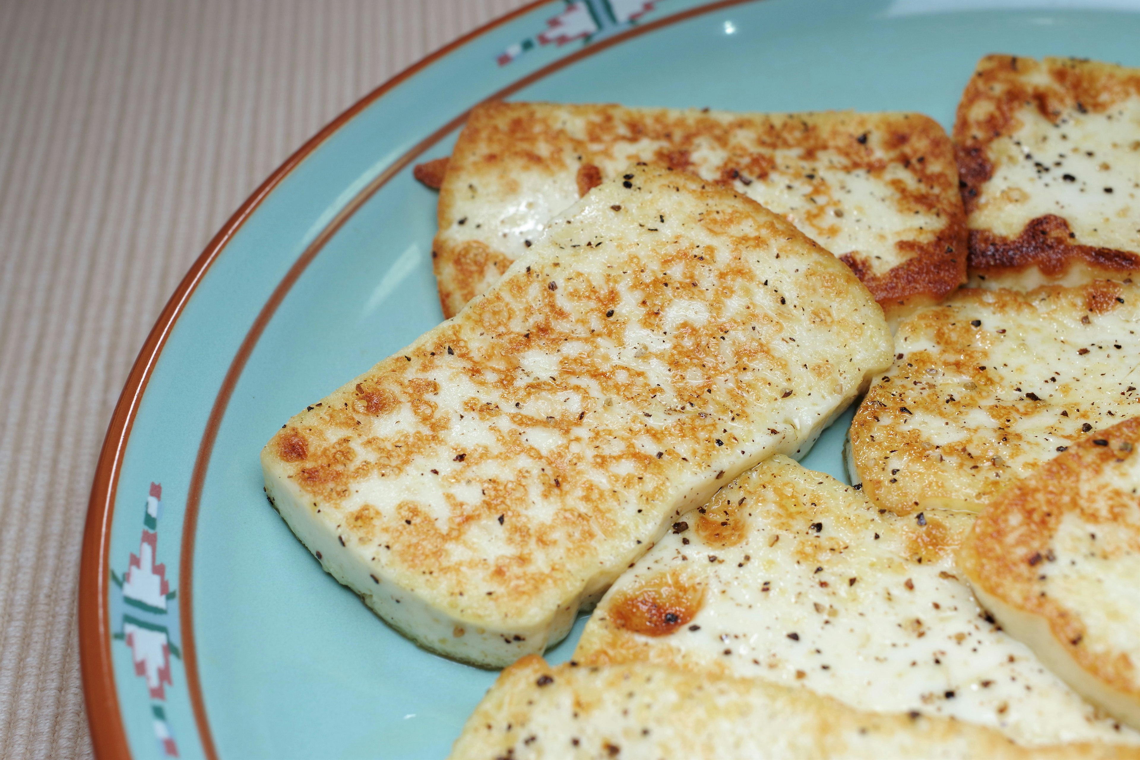 Goldbraune Scheiben von gegrilltem Tofu auf einem dekorativen Teller