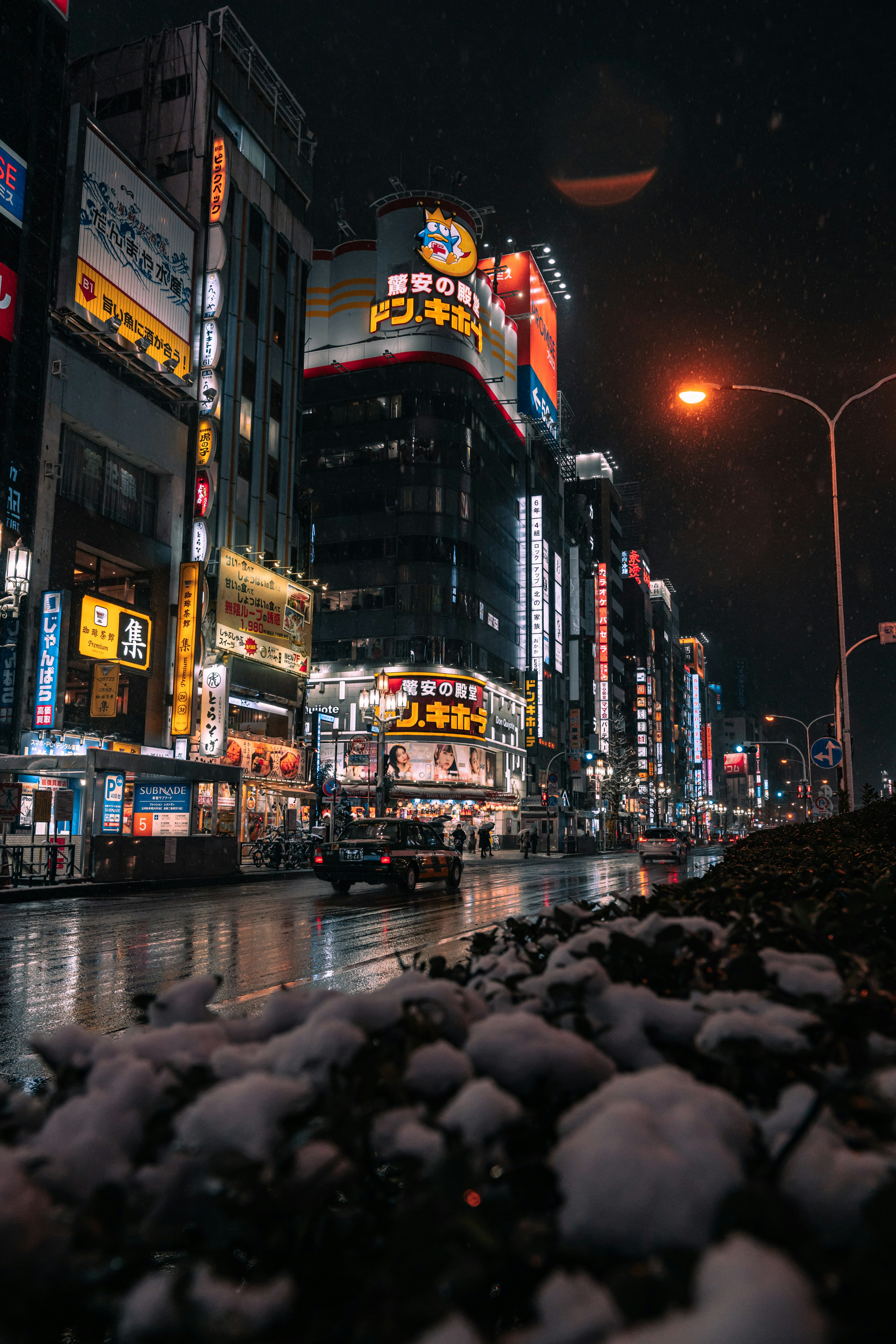 夜の都市景観に雪が残る通りとネオンの看板