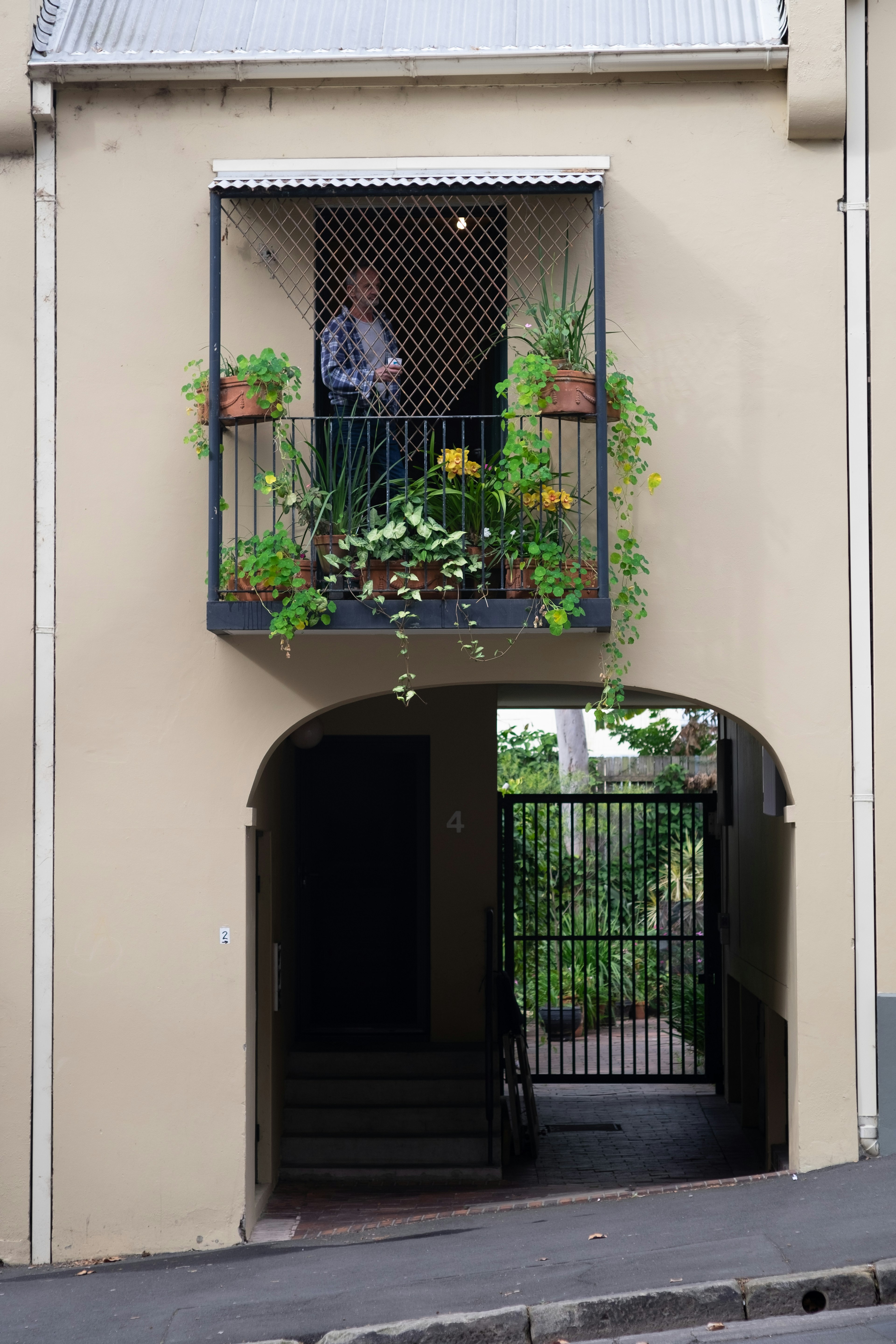 Esterno di un edificio con un balcone adornato di piante e una persona in piedi sopra