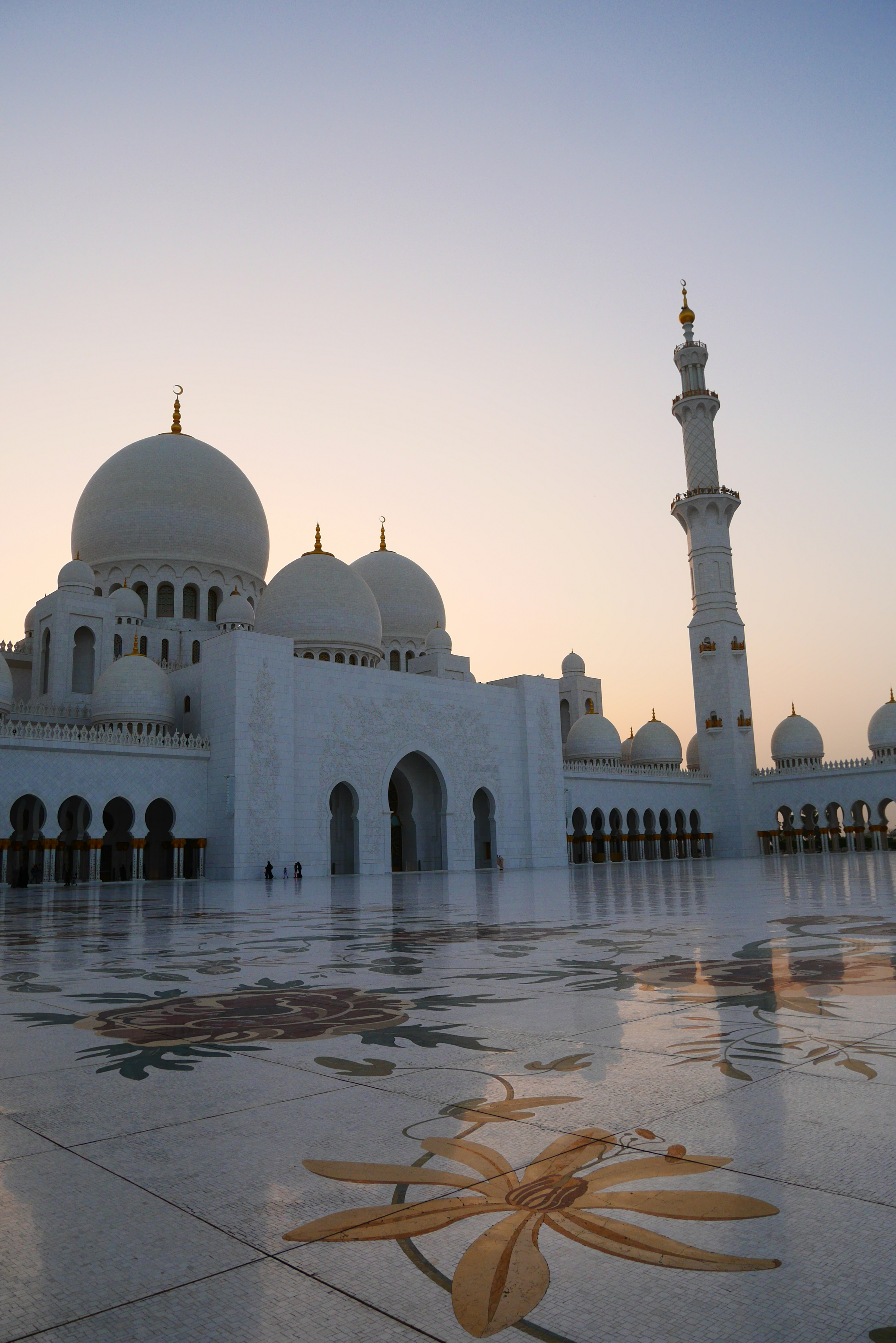 Schöne Aussicht auf die Sheikh-Zayed-Moschee mit weißen Kuppeln und Minarett, beleuchtet bei Sonnenuntergang