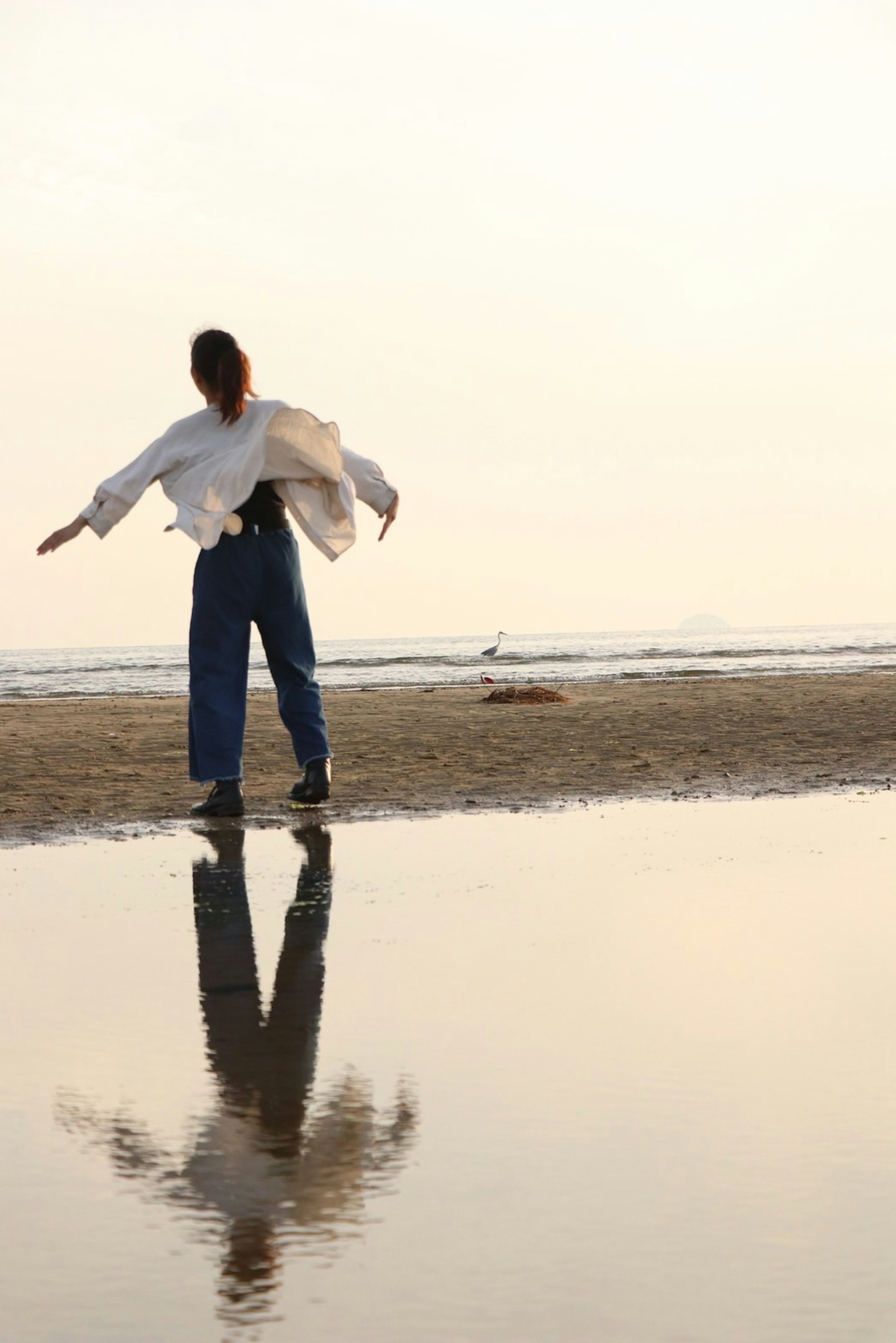 Silhouette of a woman by the sea reflecting in water with soft sunlight