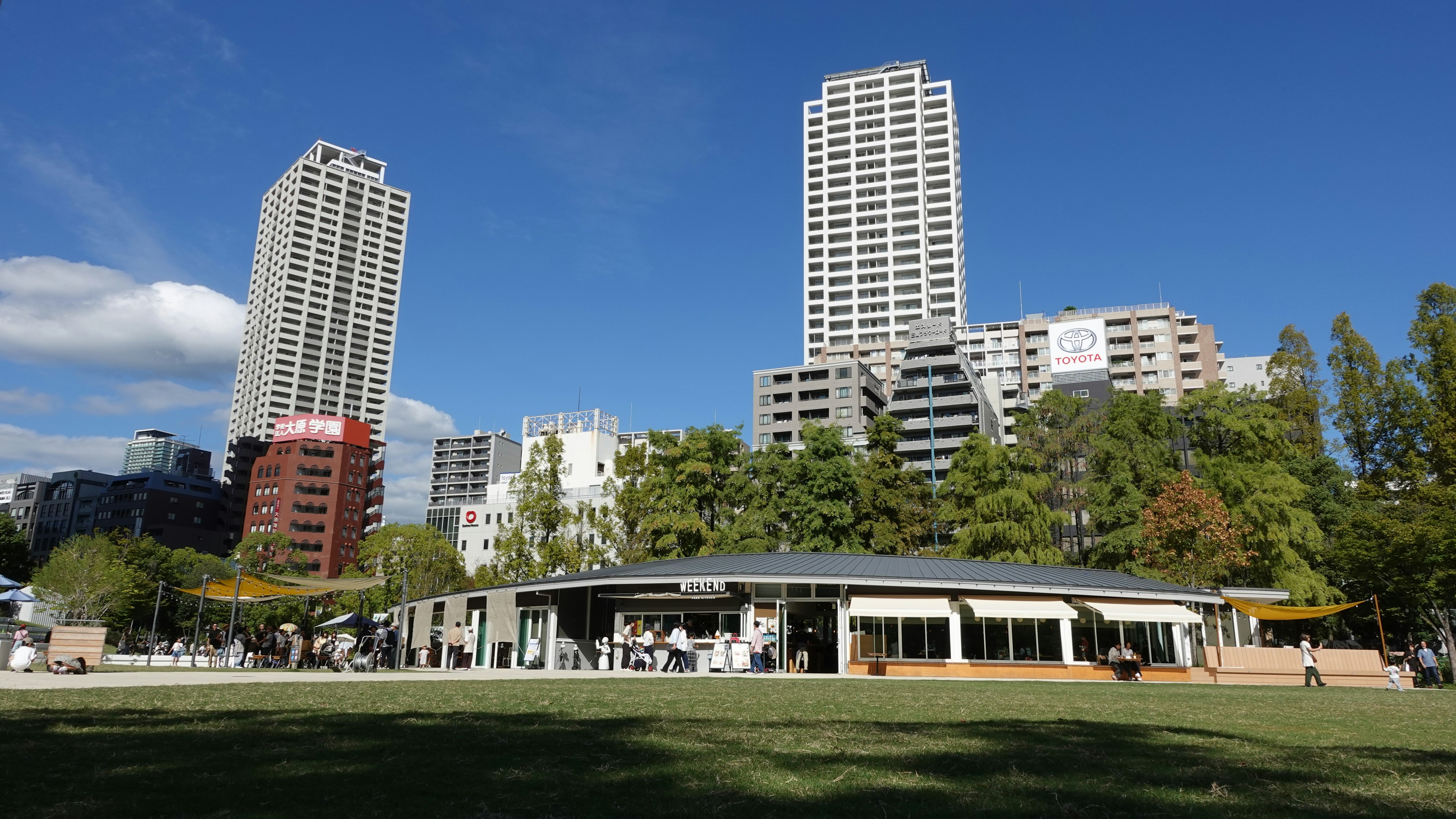 Paisaje urbano con edificios altos y un parque verde con terraza de café