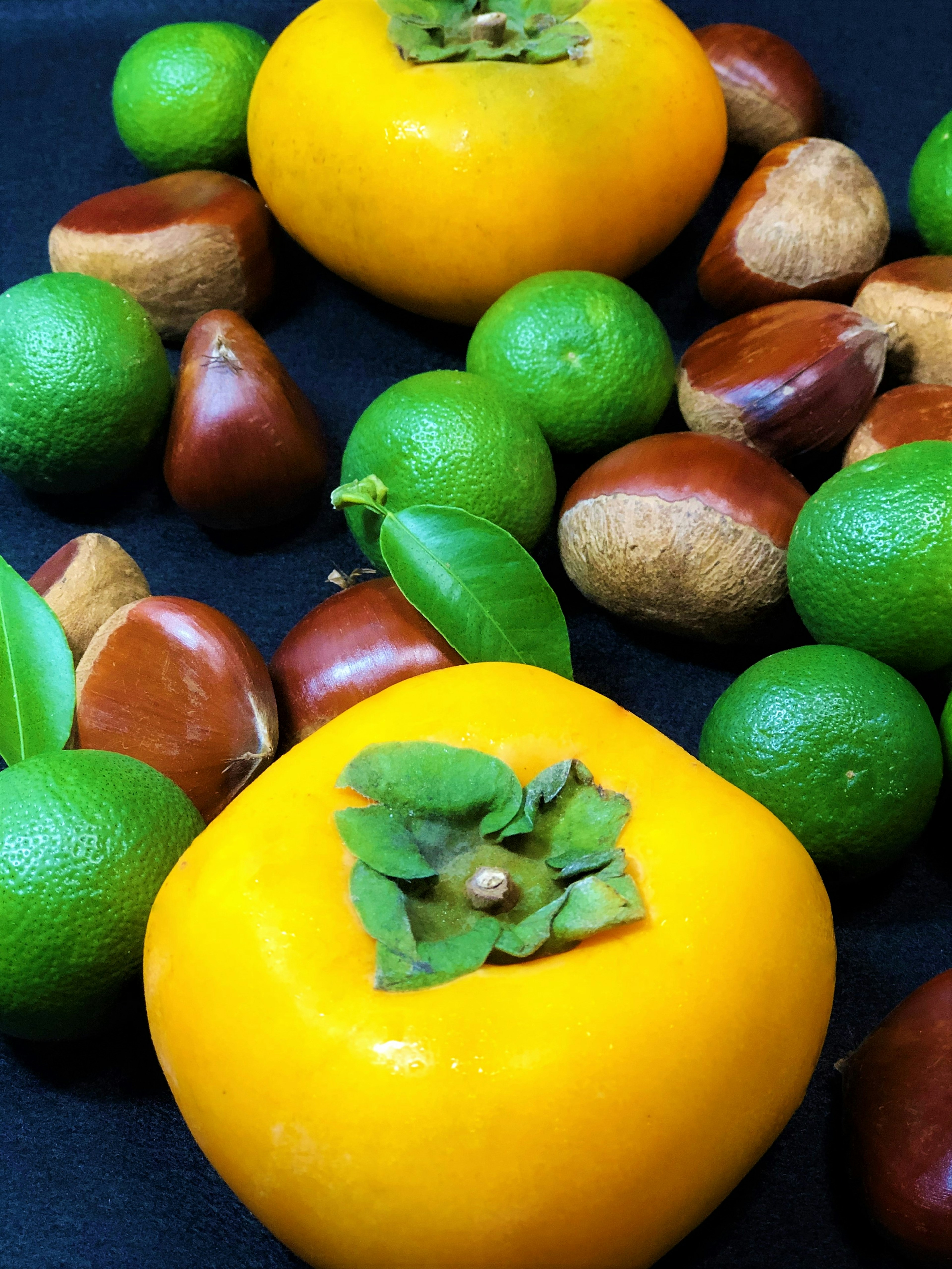 Vibrant still life featuring yellow persimmons and green fruits