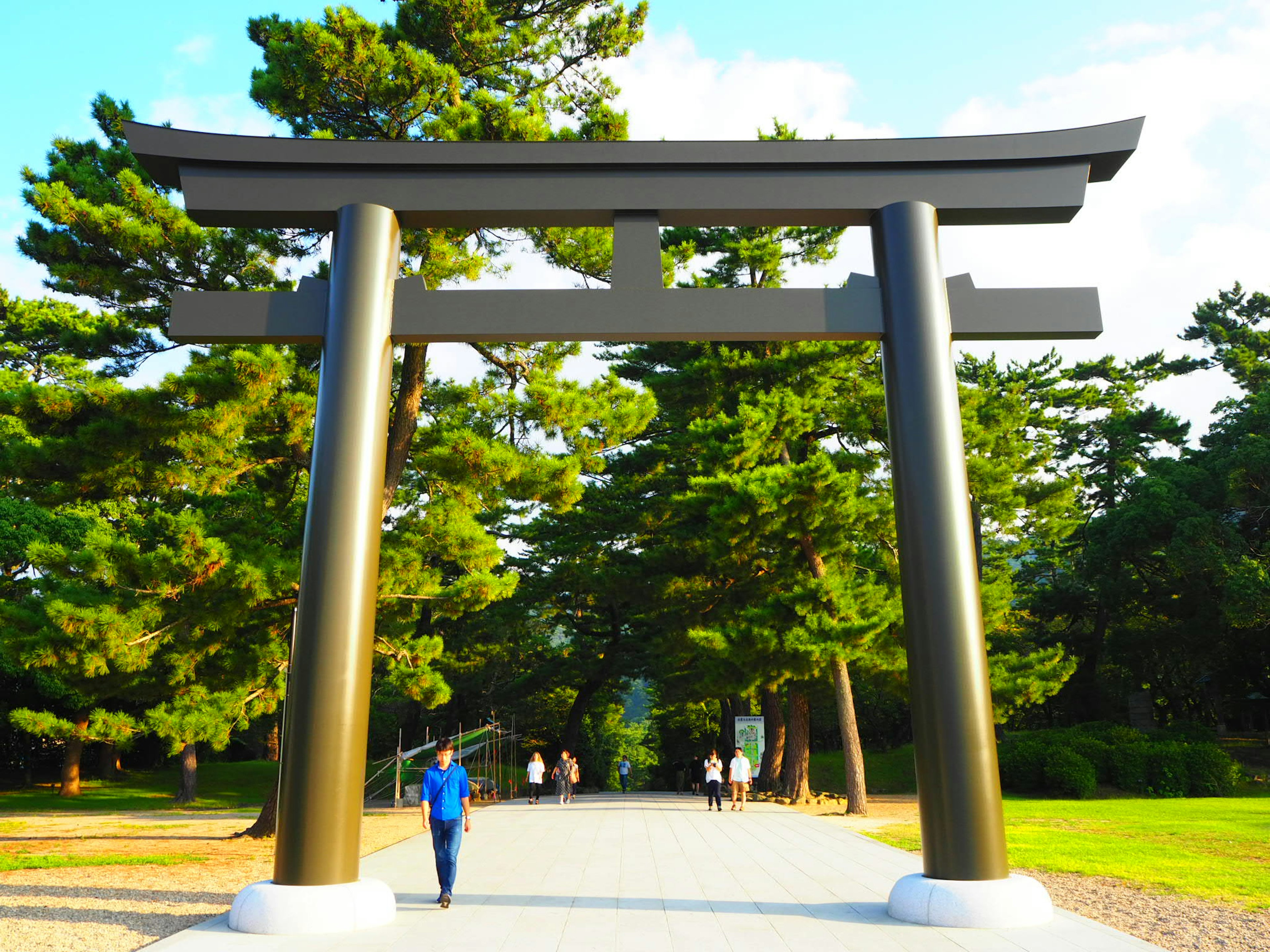 Large black torii gate in a park scene People walking surrounded by green trees