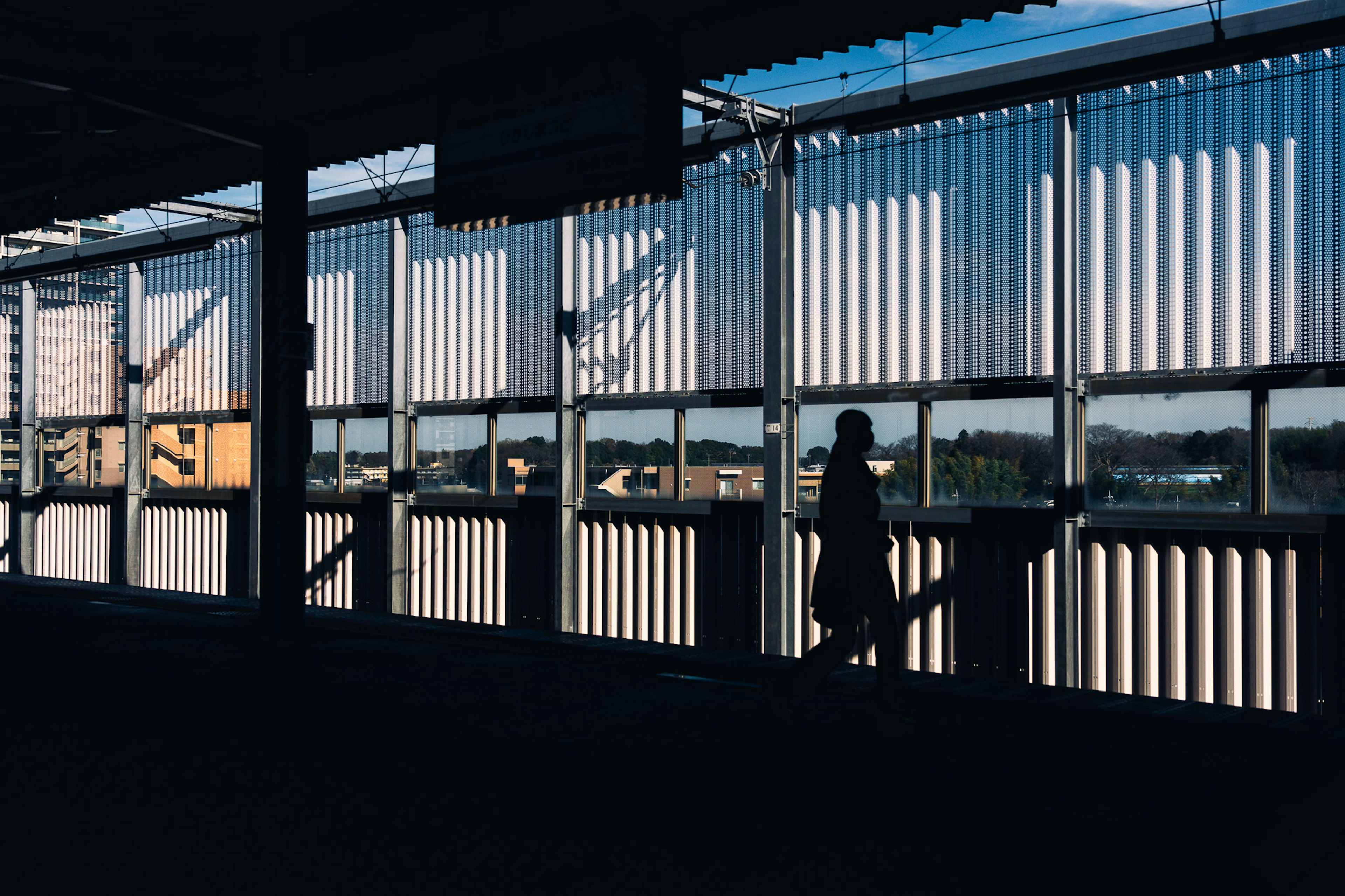 Silhouette di una persona in piedi in un'area d'attesa di una stazione ben illuminata