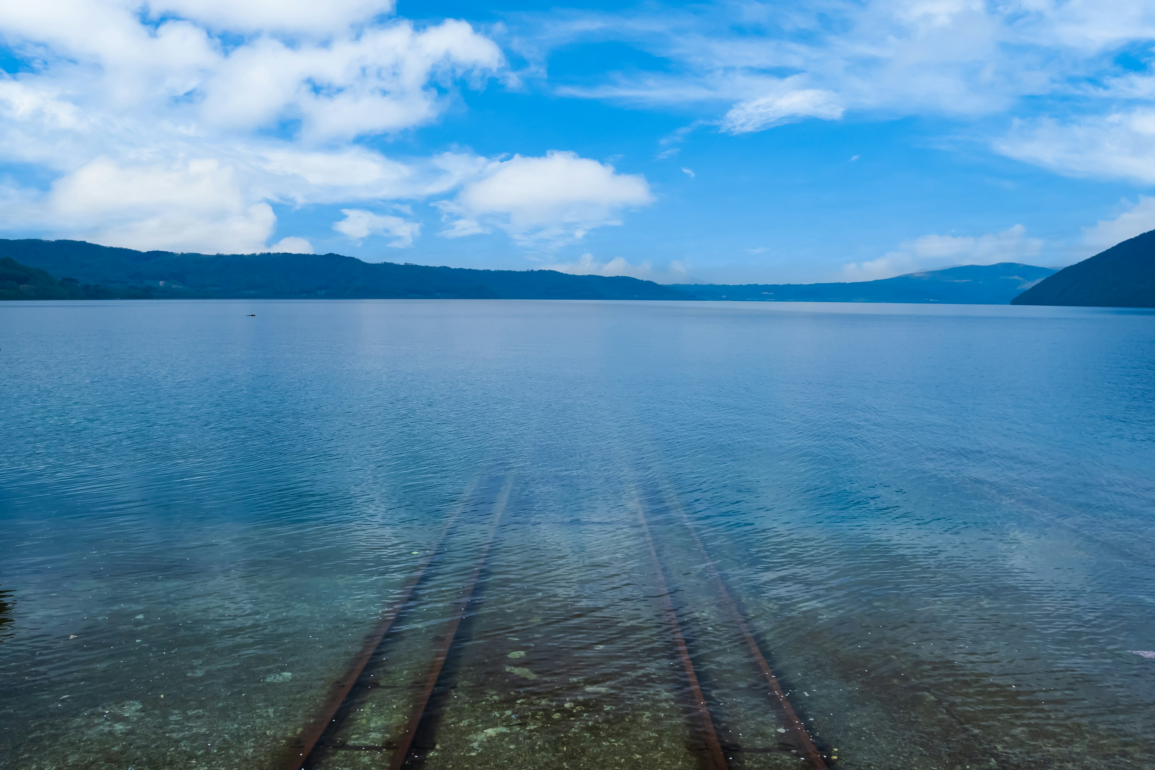 Acqua chiara che riflette il cielo blu e le montagne