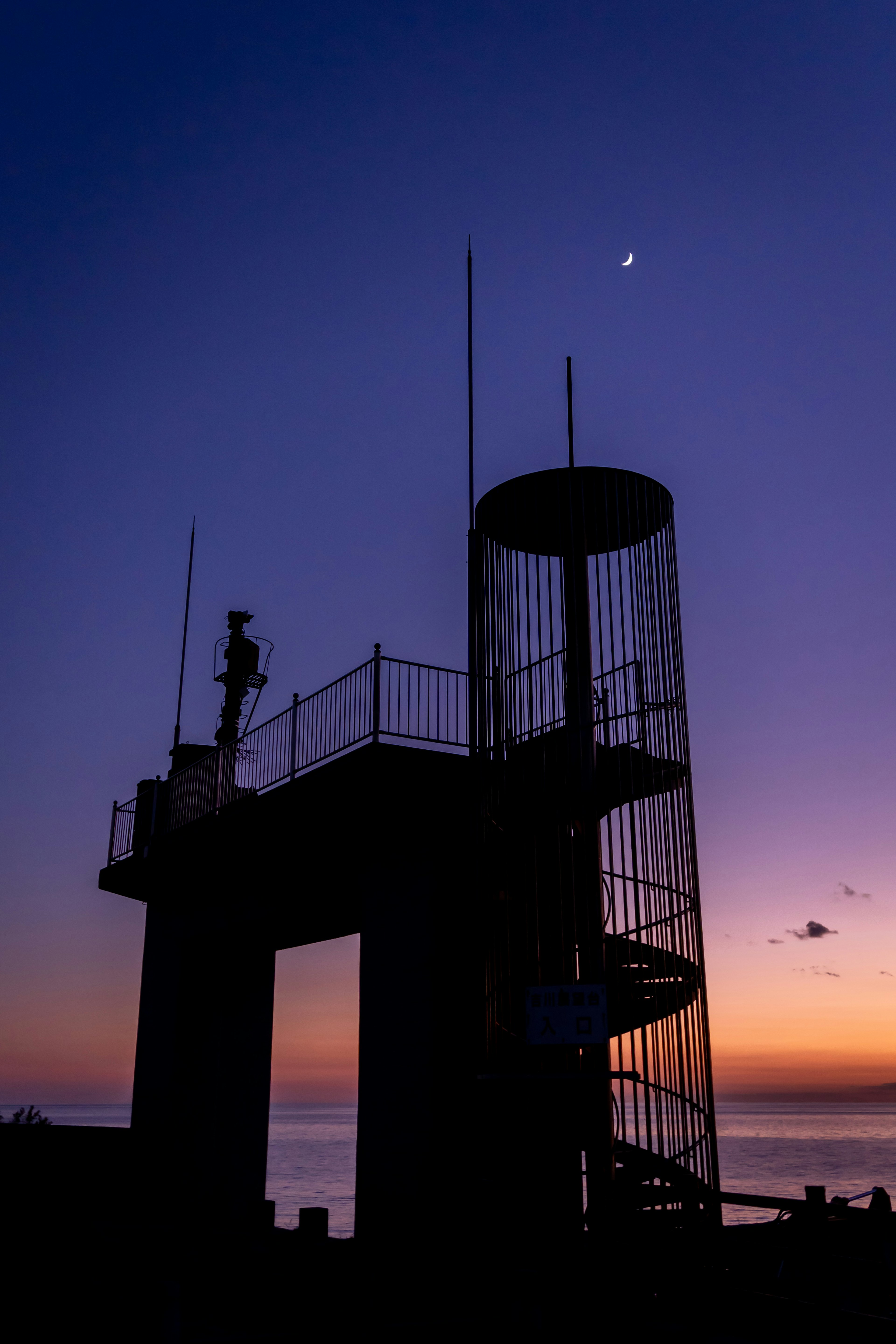 Silhouette of a watchtower with a spiral staircase against a sunset