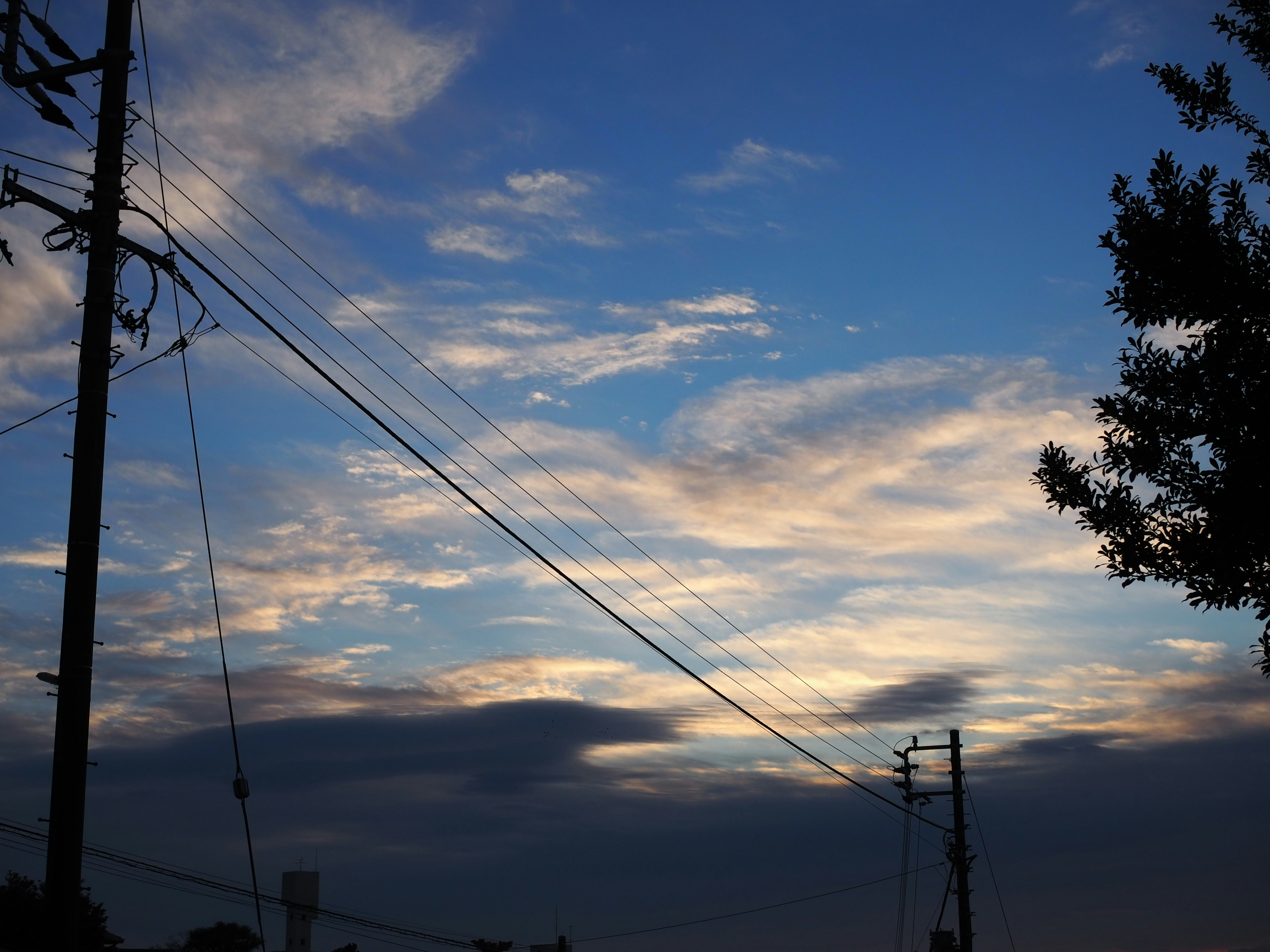 Silueta de postes eléctricos contra un cielo azul con nubes