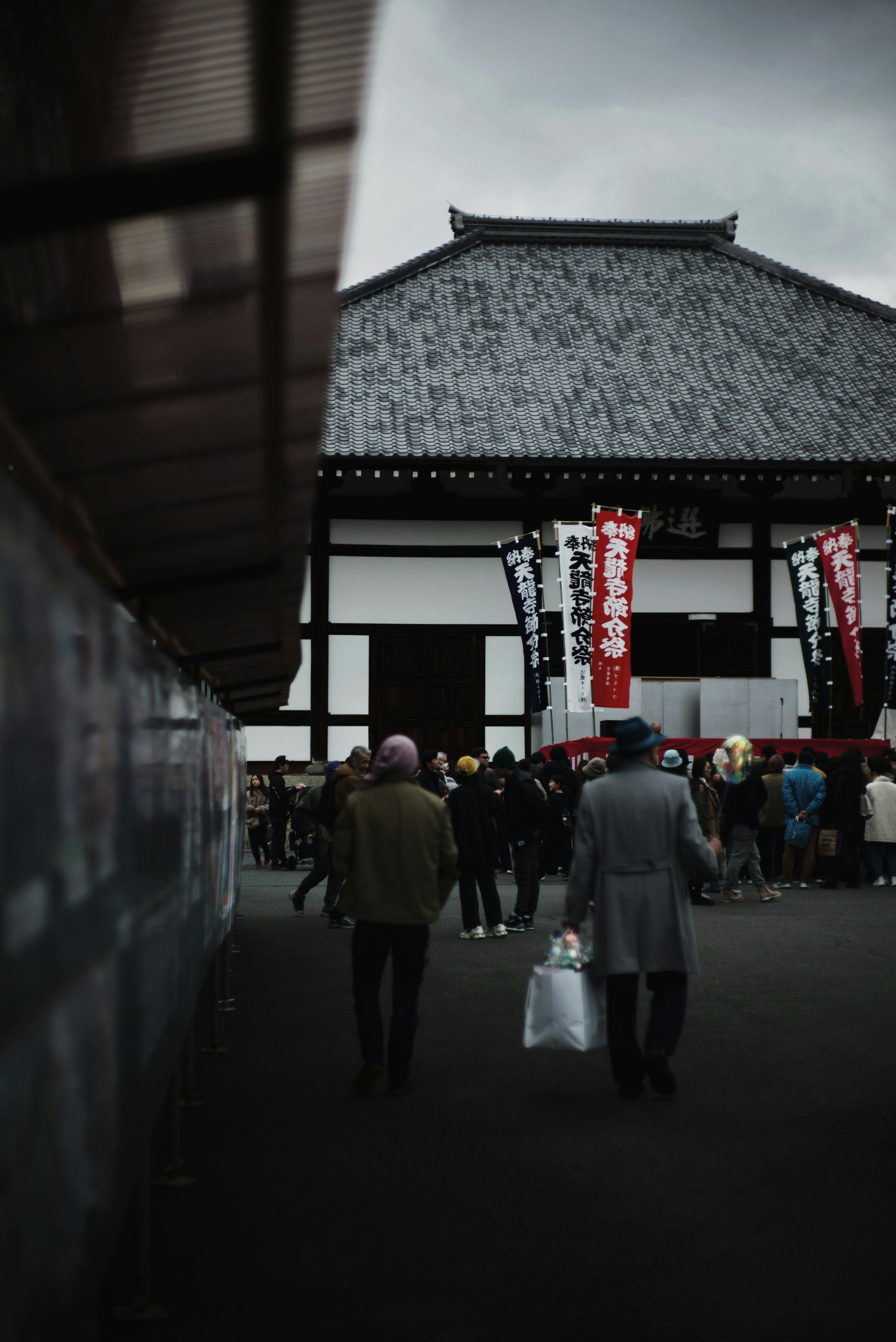 Hombres caminando frente a un edificio japonés tradicional con pancartas