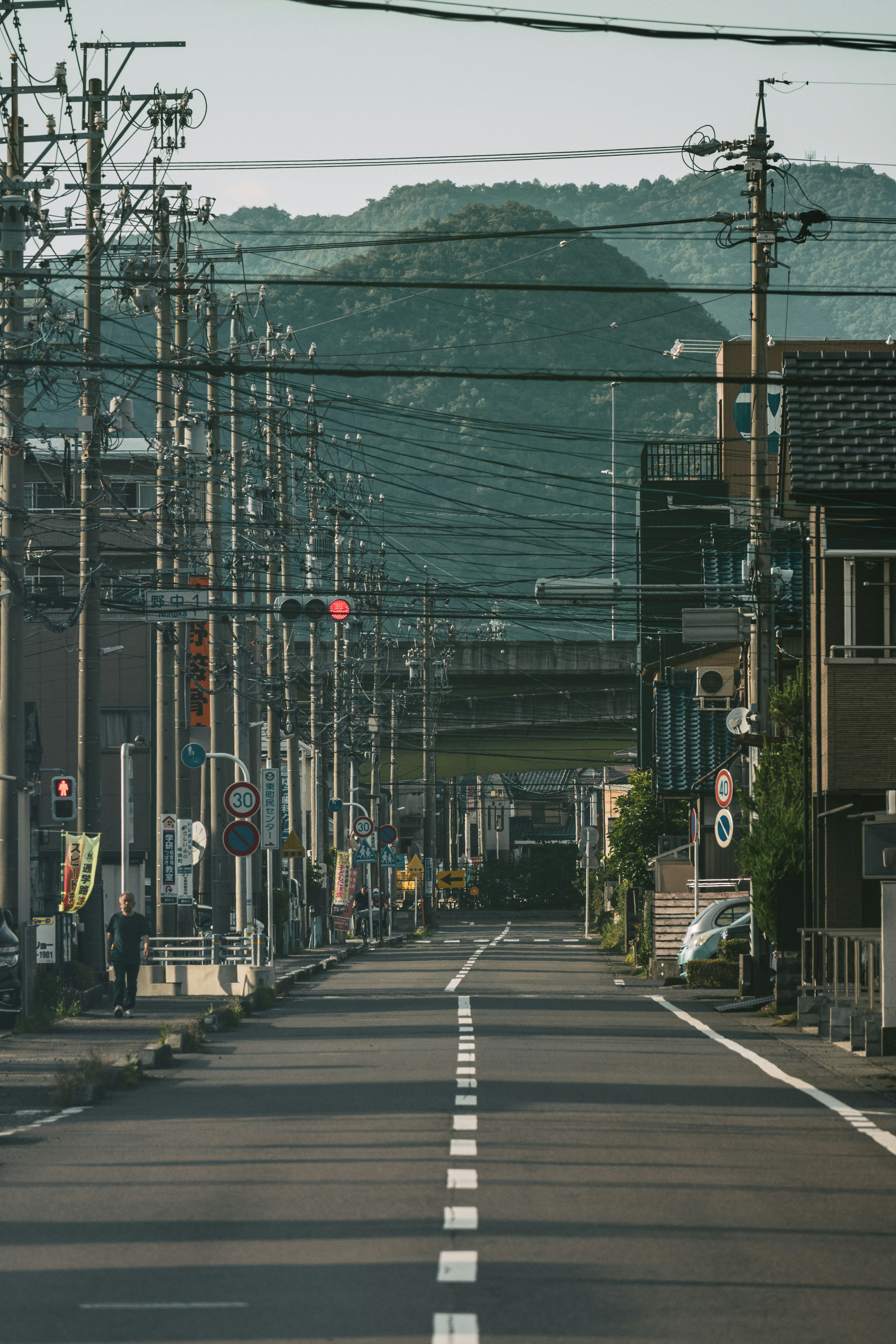 Quiet street scene featuring a road lined with utility poles green mountains in the background