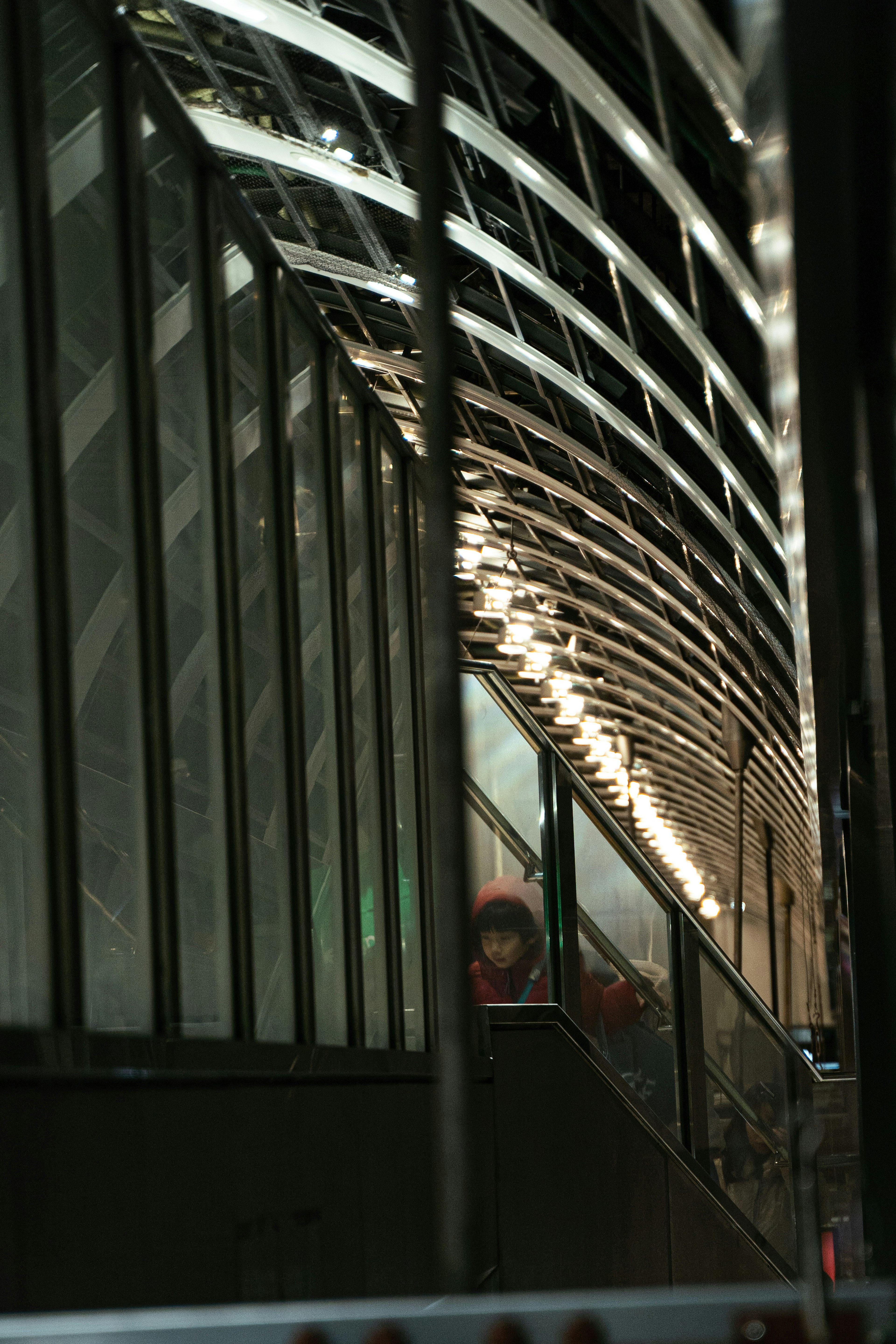 A corridor with reflective glass walls and curved metal structures