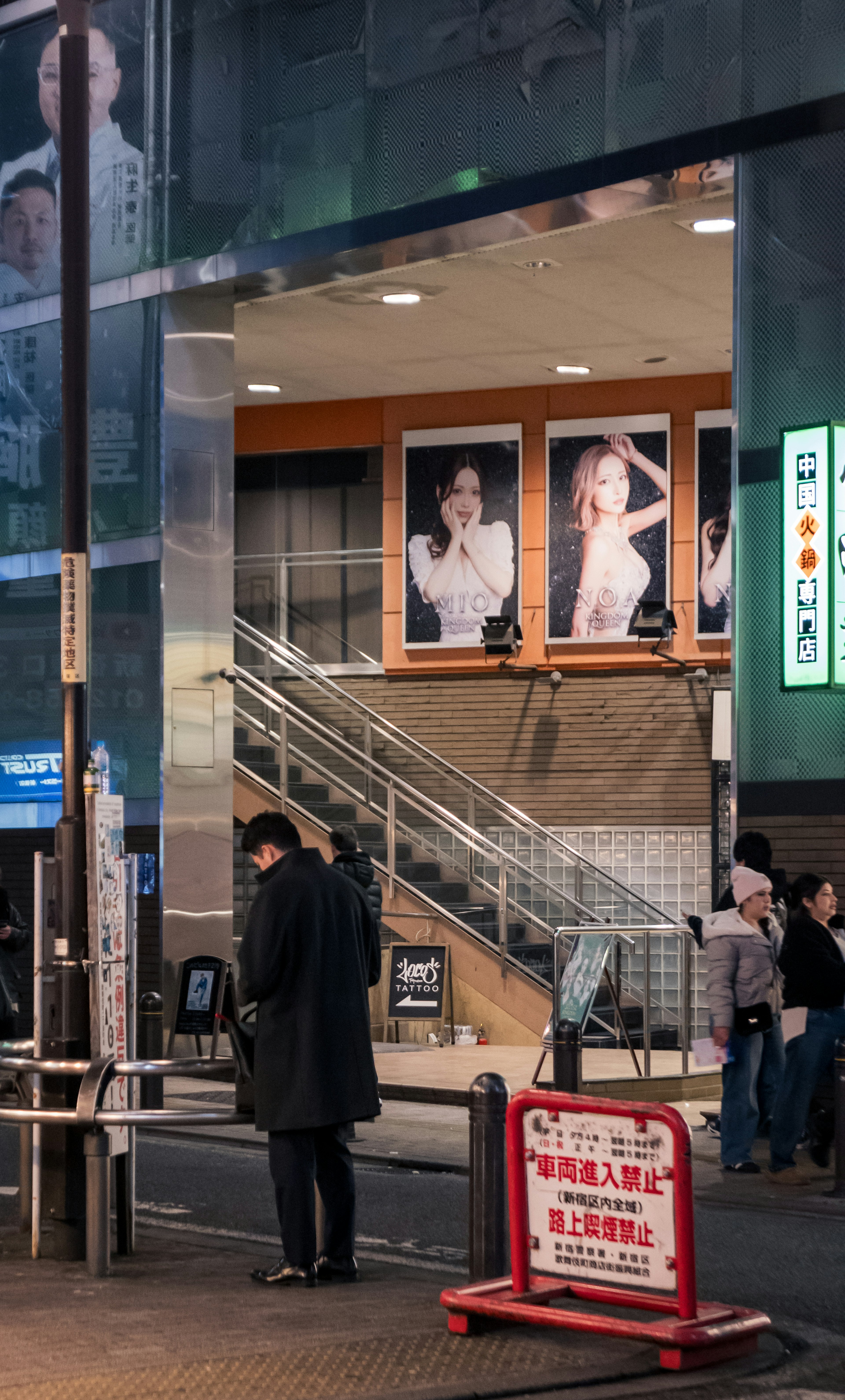 Scène avec des escaliers et de grands panneaux publicitaires dans un cadre urbain nocturne