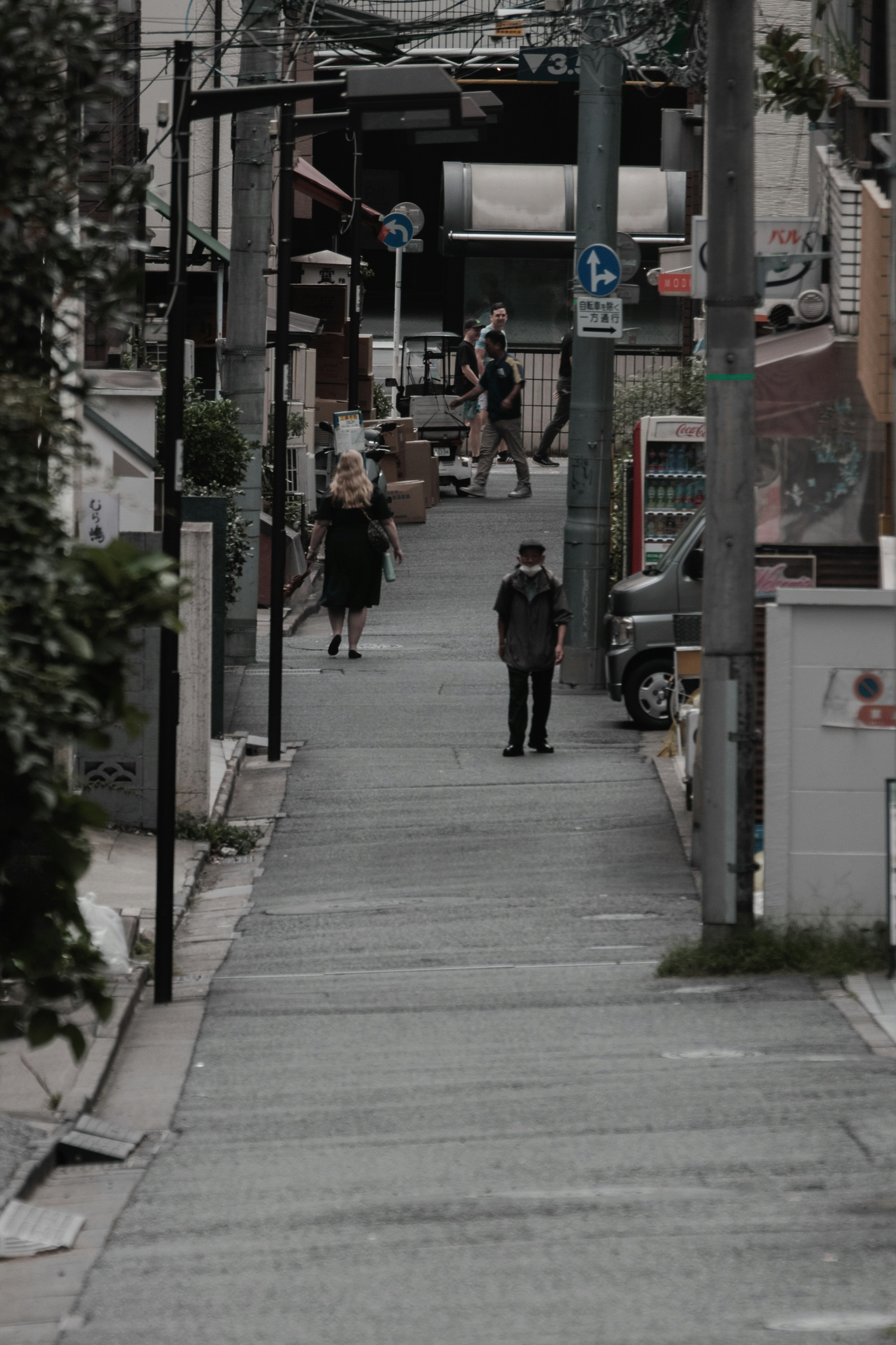 A narrow street with people walking and shops visible