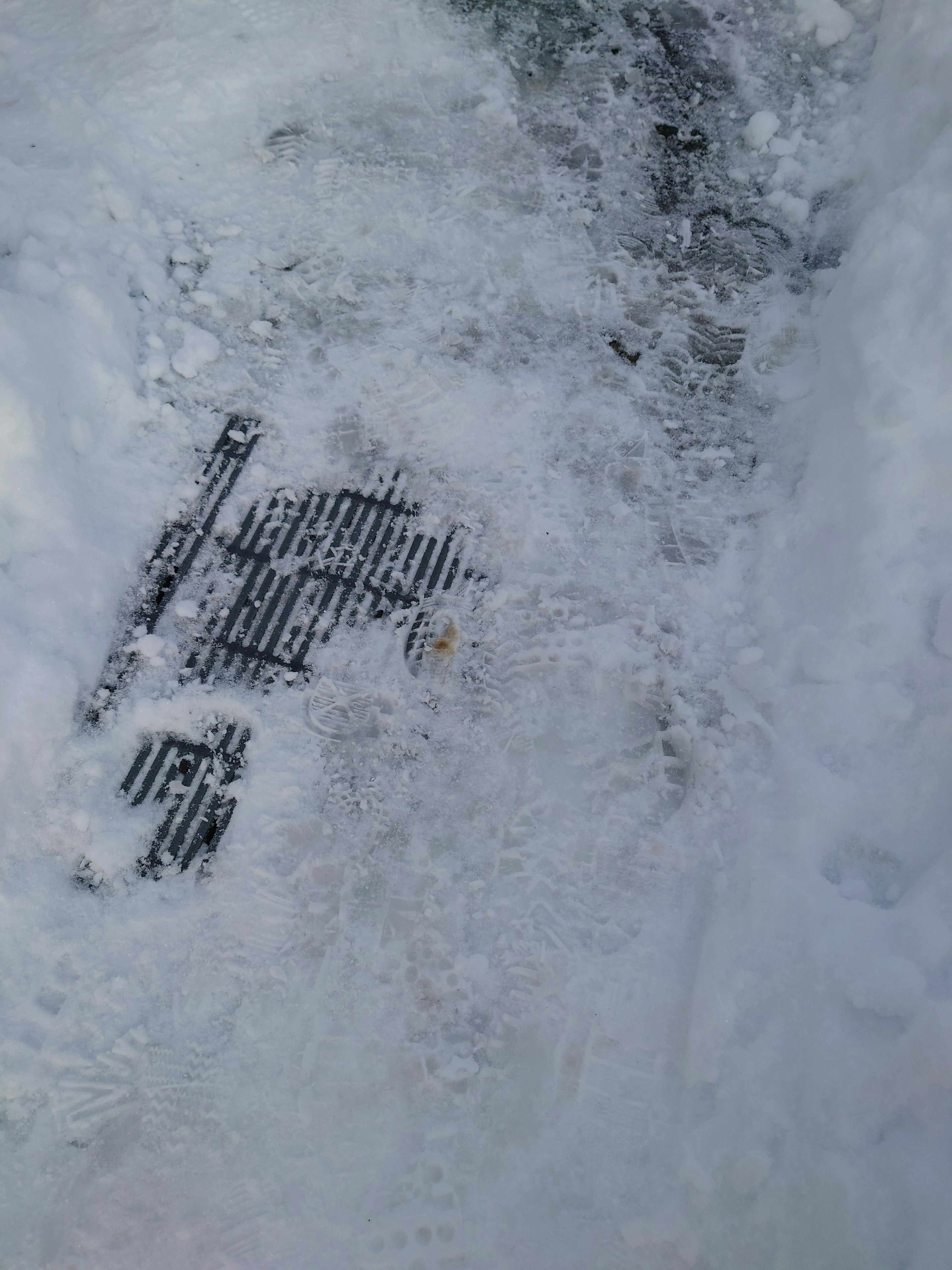 雪に覆われた道の一部に見える金属のグレーチング