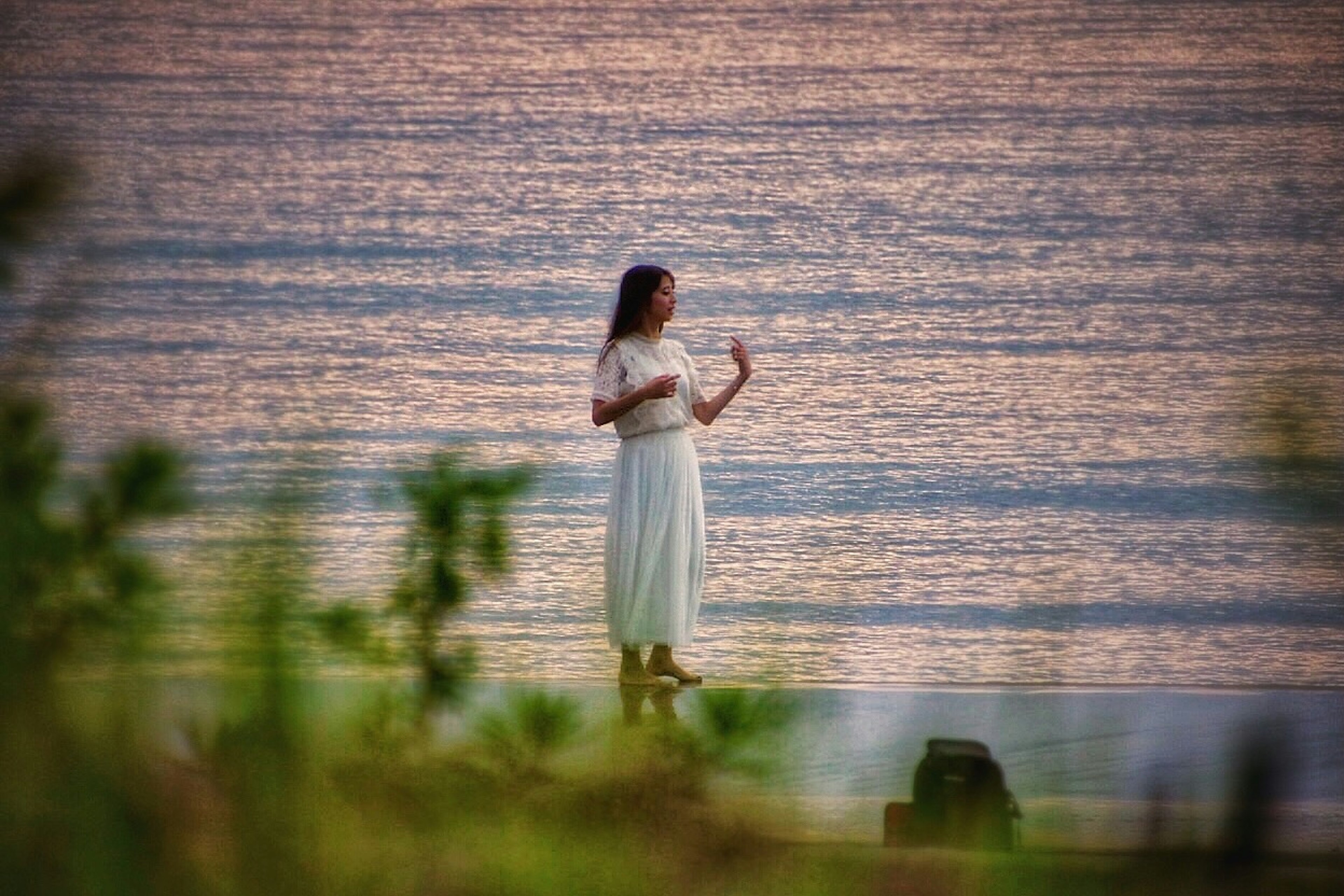 Una donna in abito bianco in piedi sulla riva