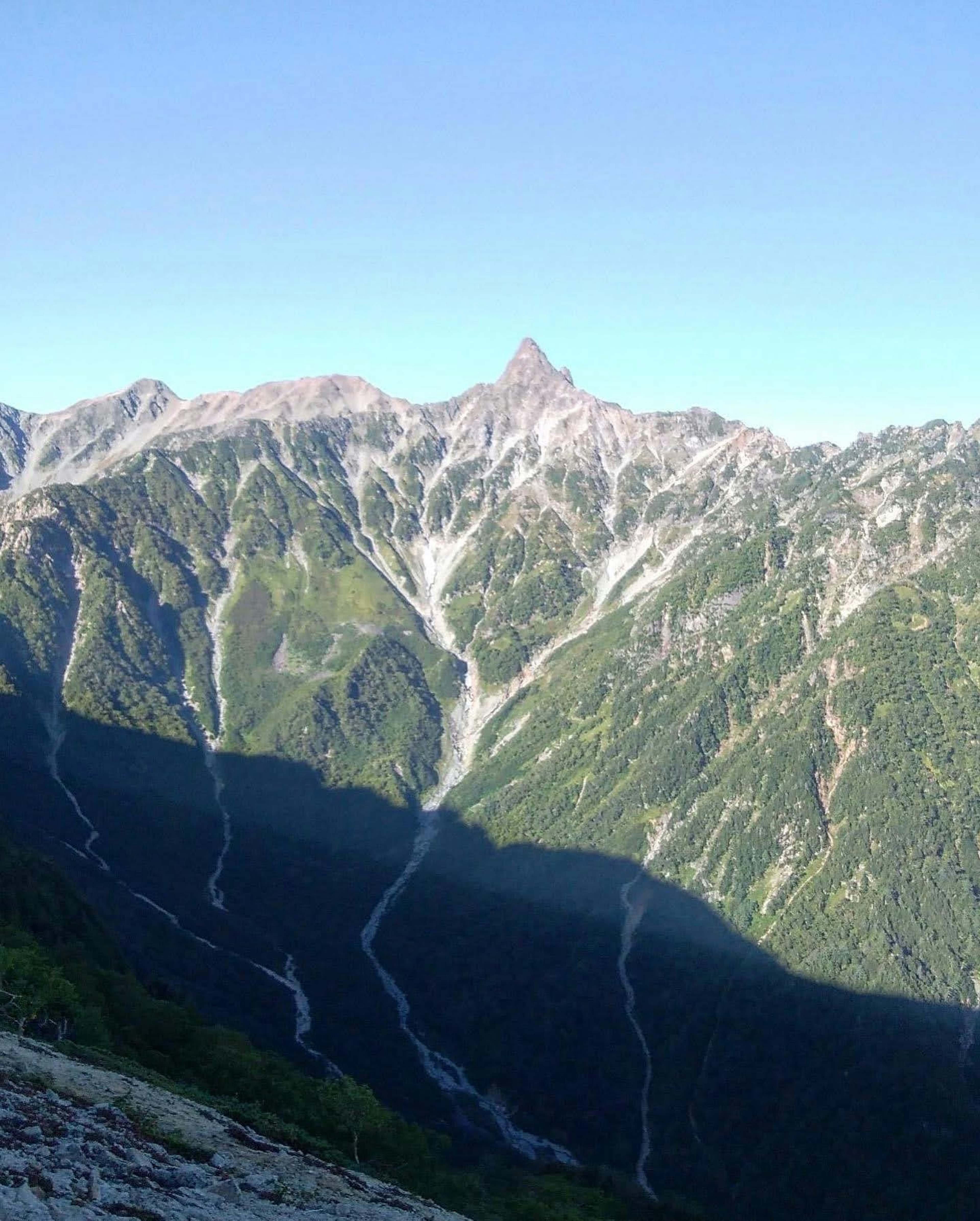 美しい山脈の景色、青い空、緑の斜面、影のある谷