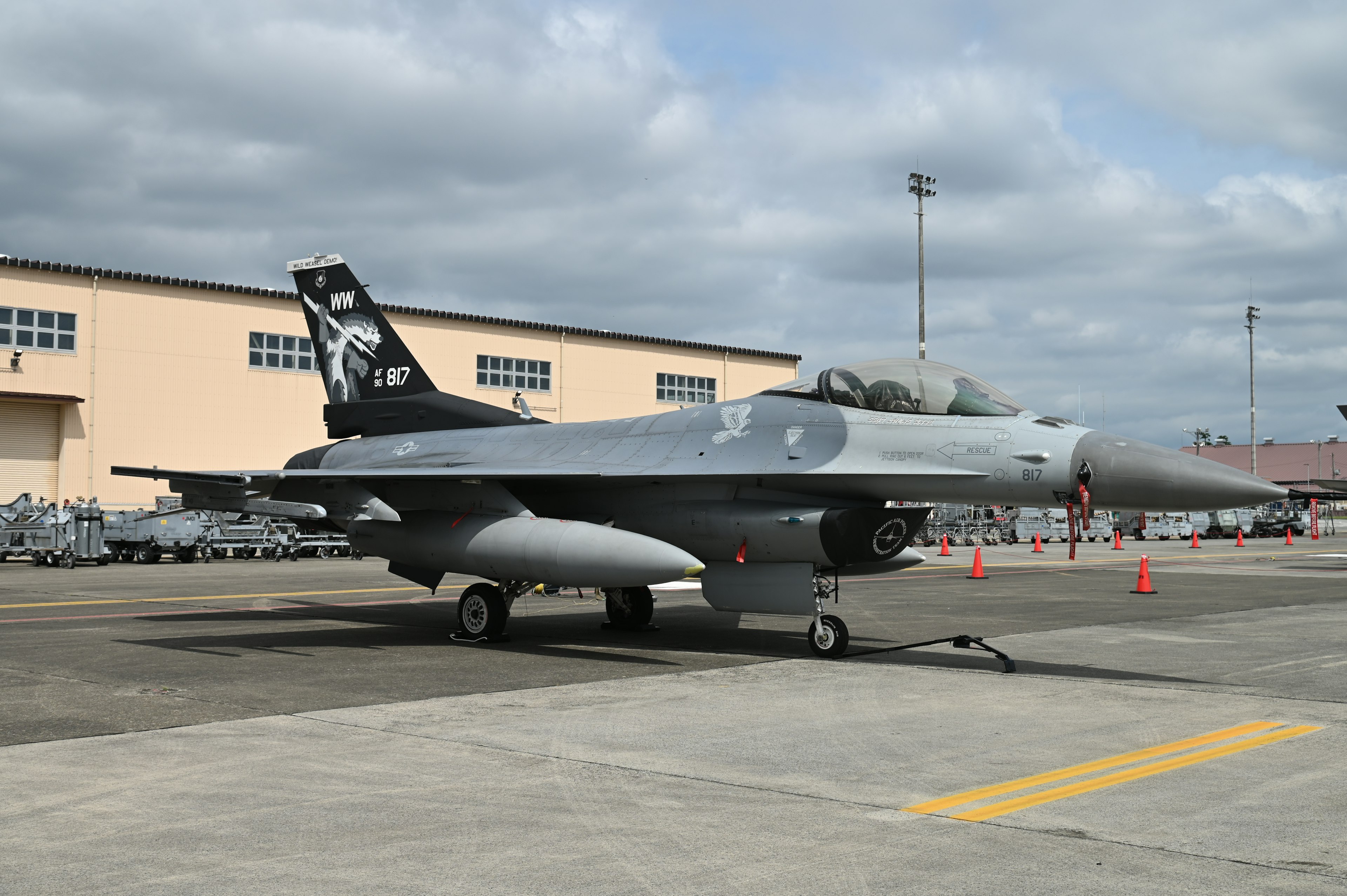 F-16 fighter jet parked on the runway with military base buildings in the background