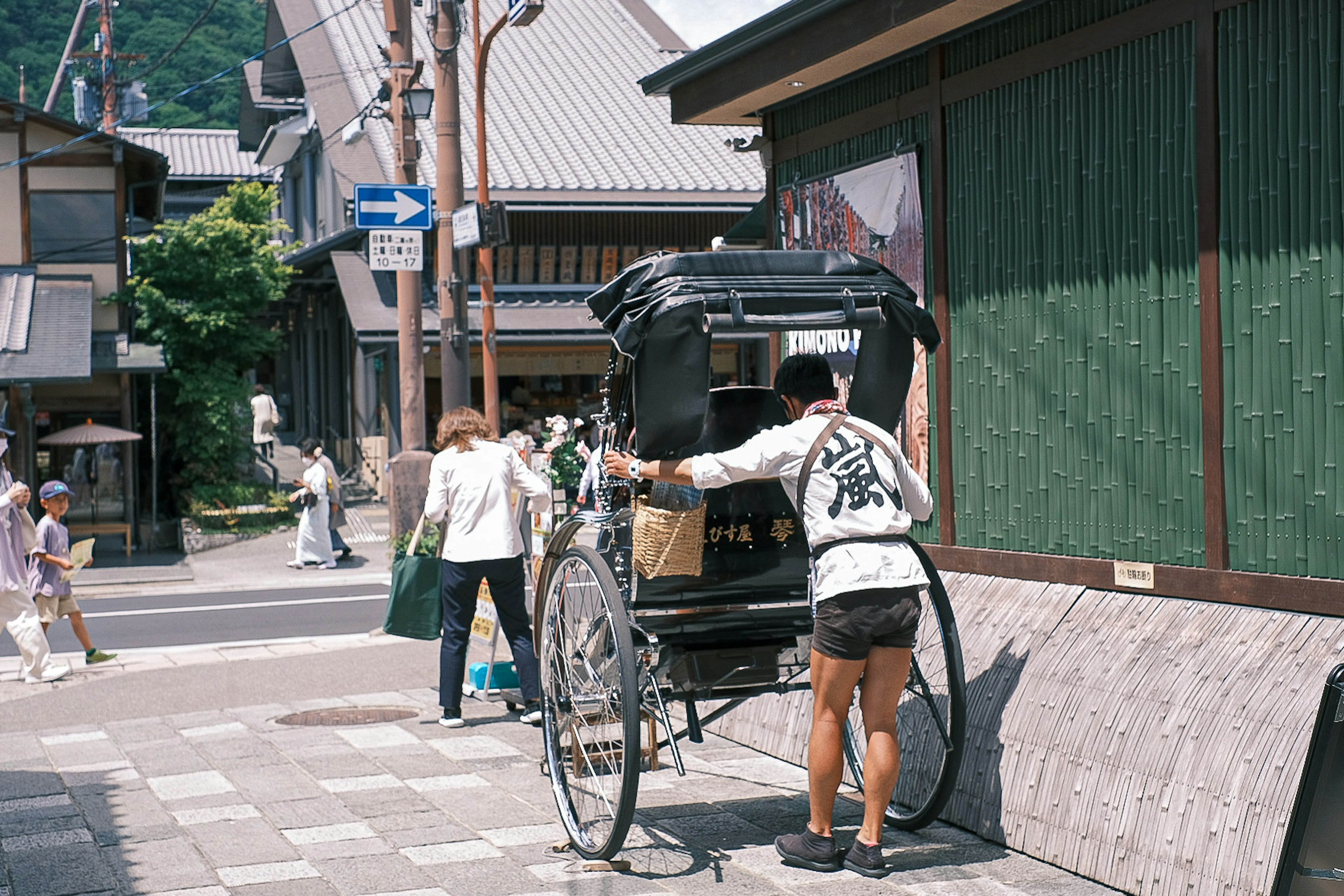 伝統的な人力車が街路に停まっている風景で運転手が準備をしている