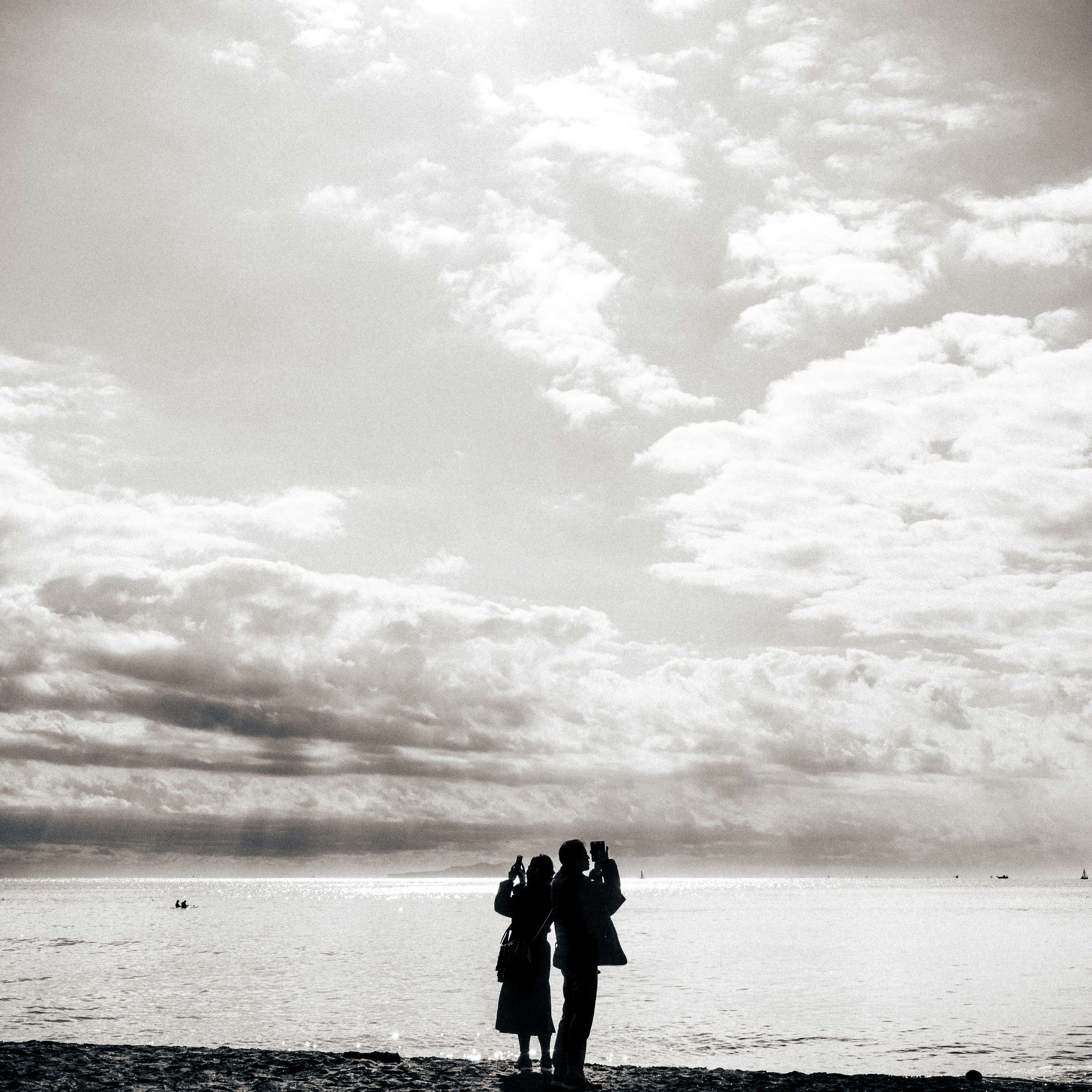 Silhouette of a couple standing by the sea in a black and white photo