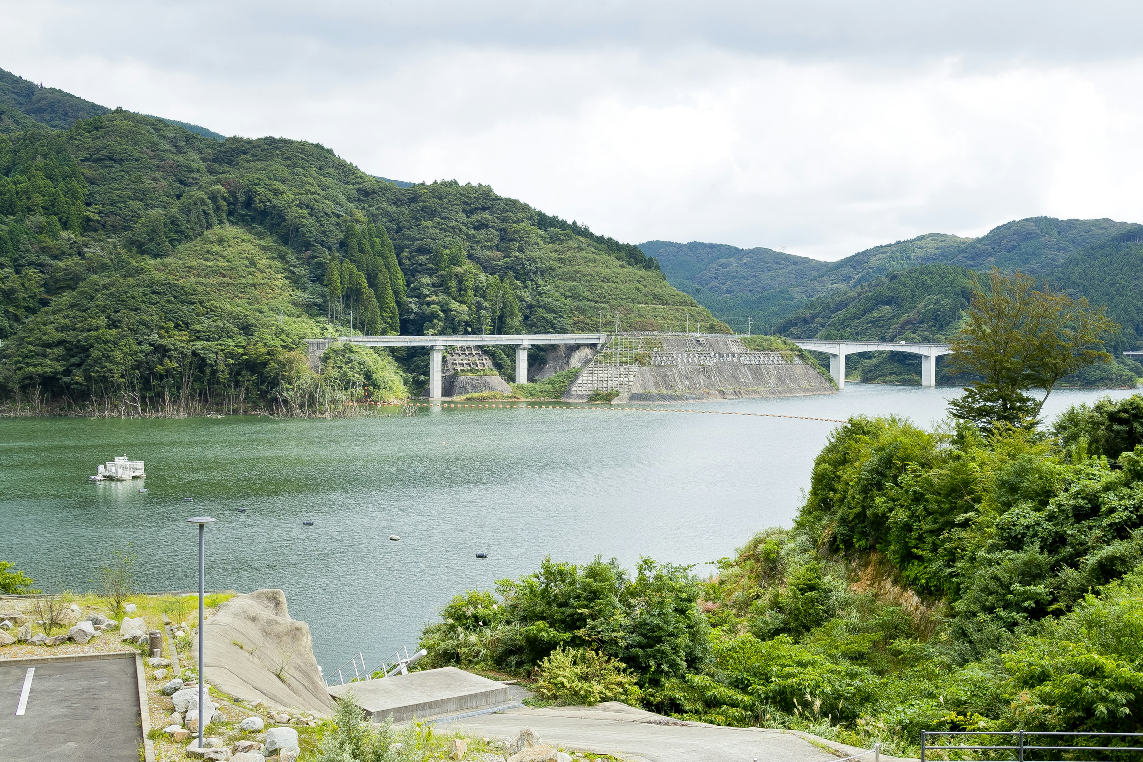 ทิวทัศน์ที่สวยงามของภูเขาเขียวขจีและทะเลสาบสงบพร้อมสะพาน