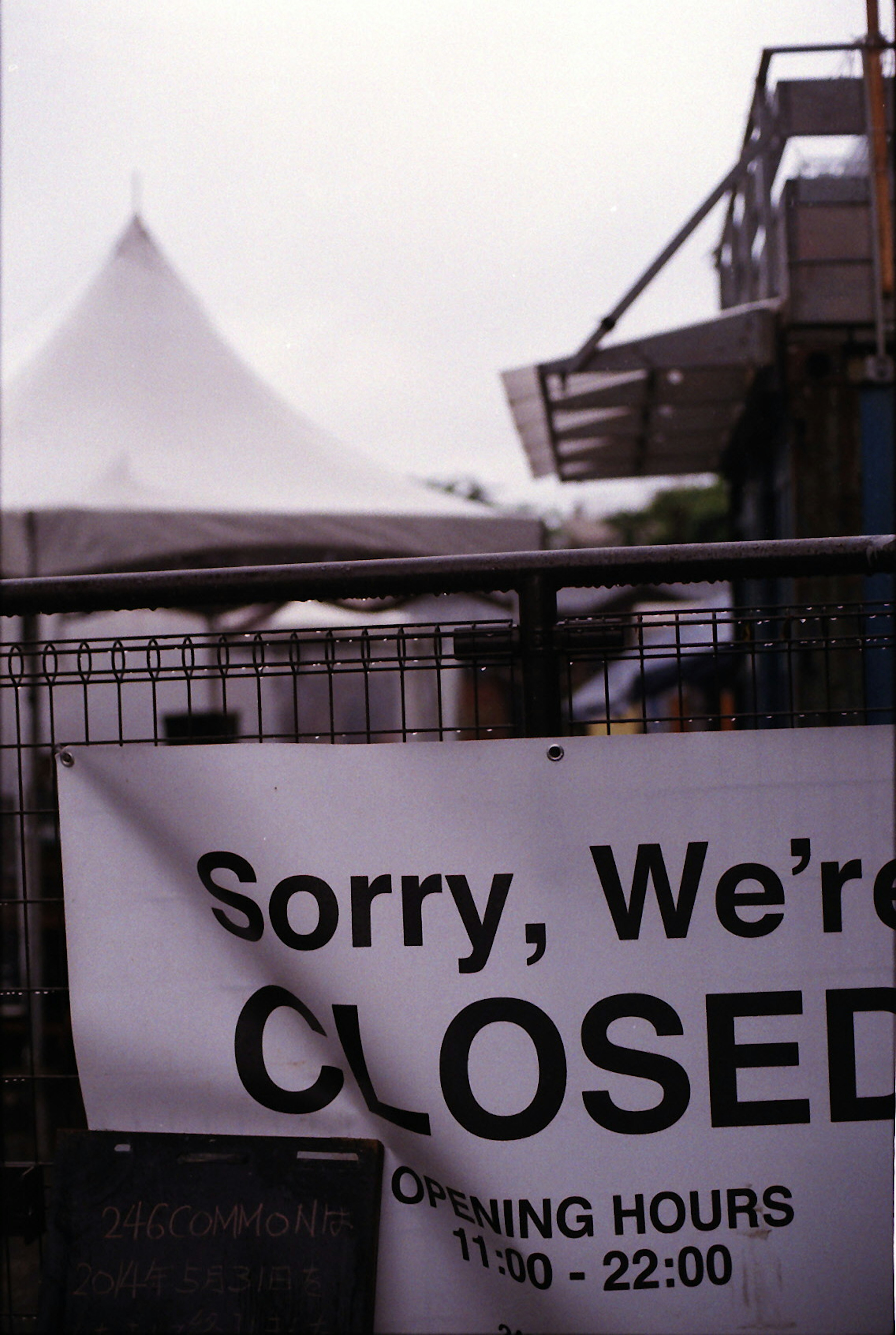 A closed sign displayed at a facility with a tent in the background