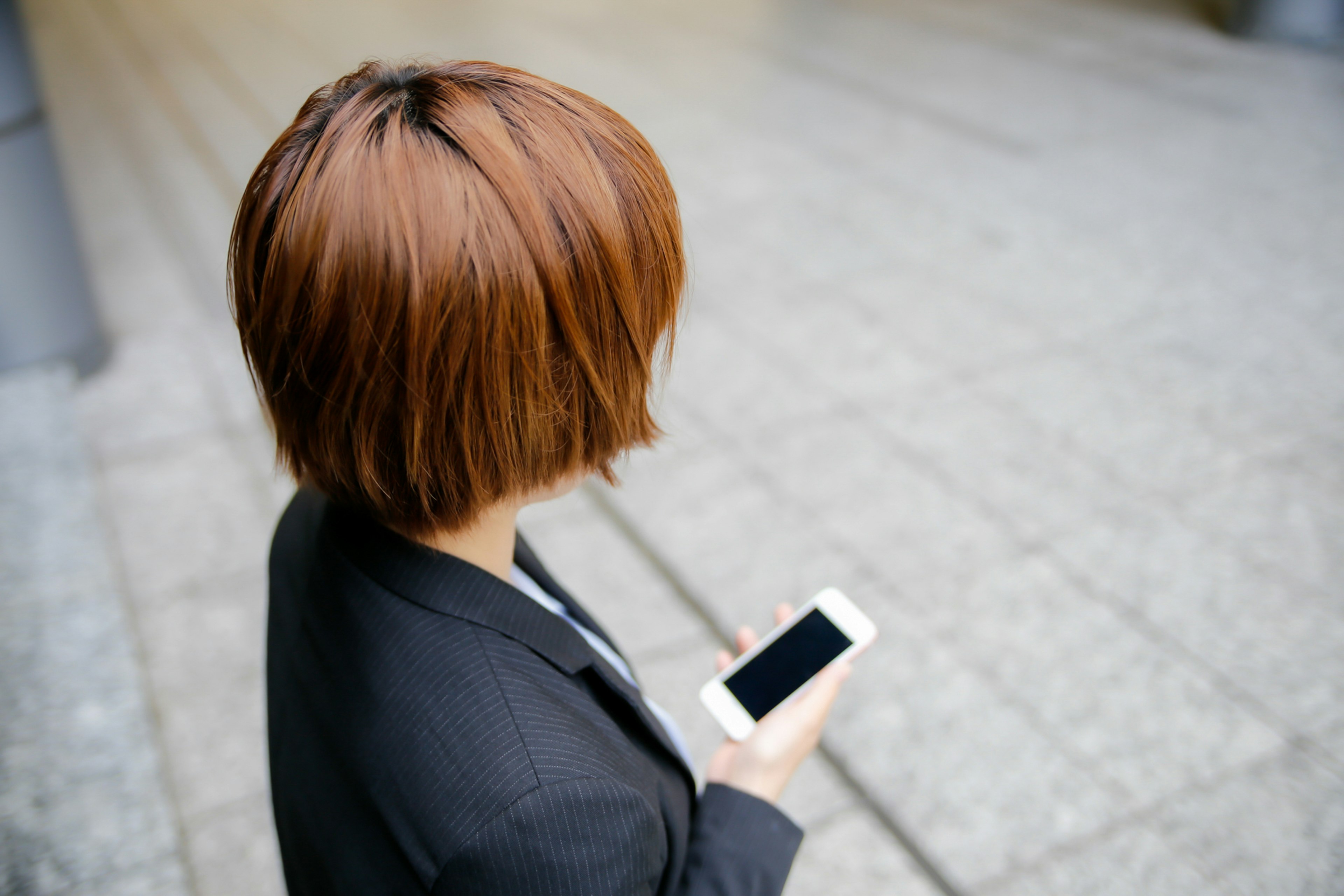 Eine Frau mit kurzen Haaren, die ein Smartphone hält