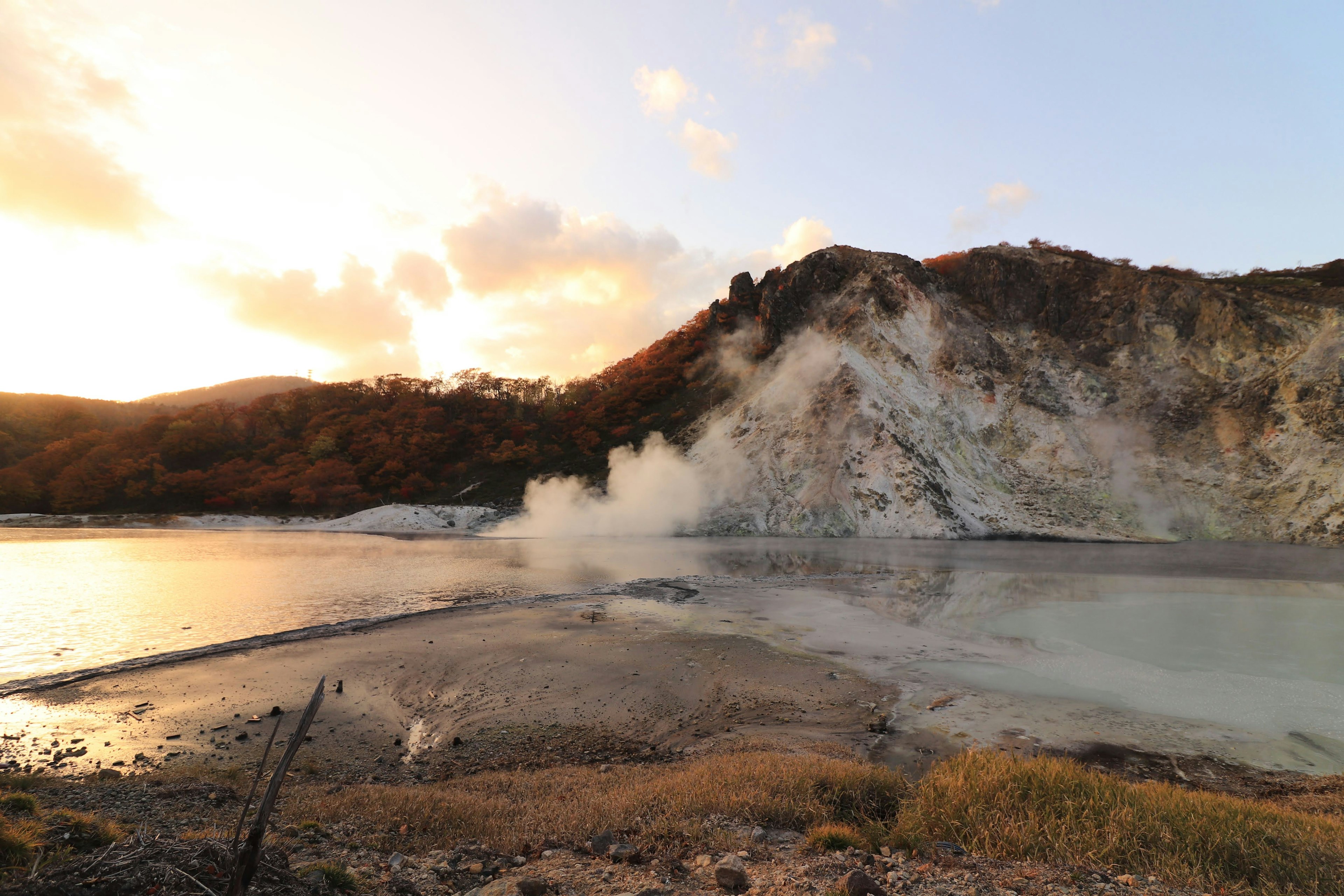 Paysage avec une source chaude fumante et une montagne au coucher du soleil