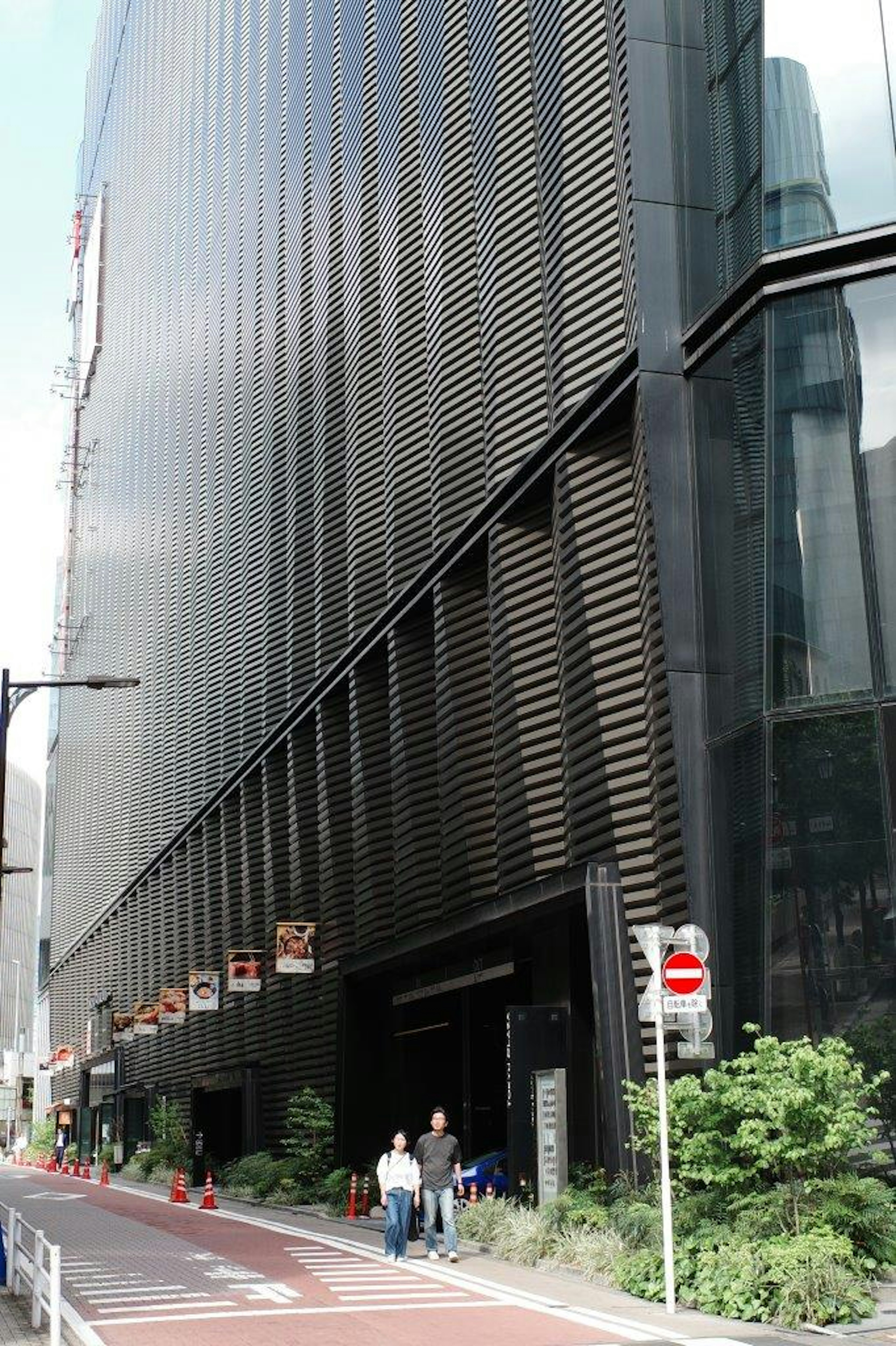 Modern building with black facade and pedestrians on the sidewalk