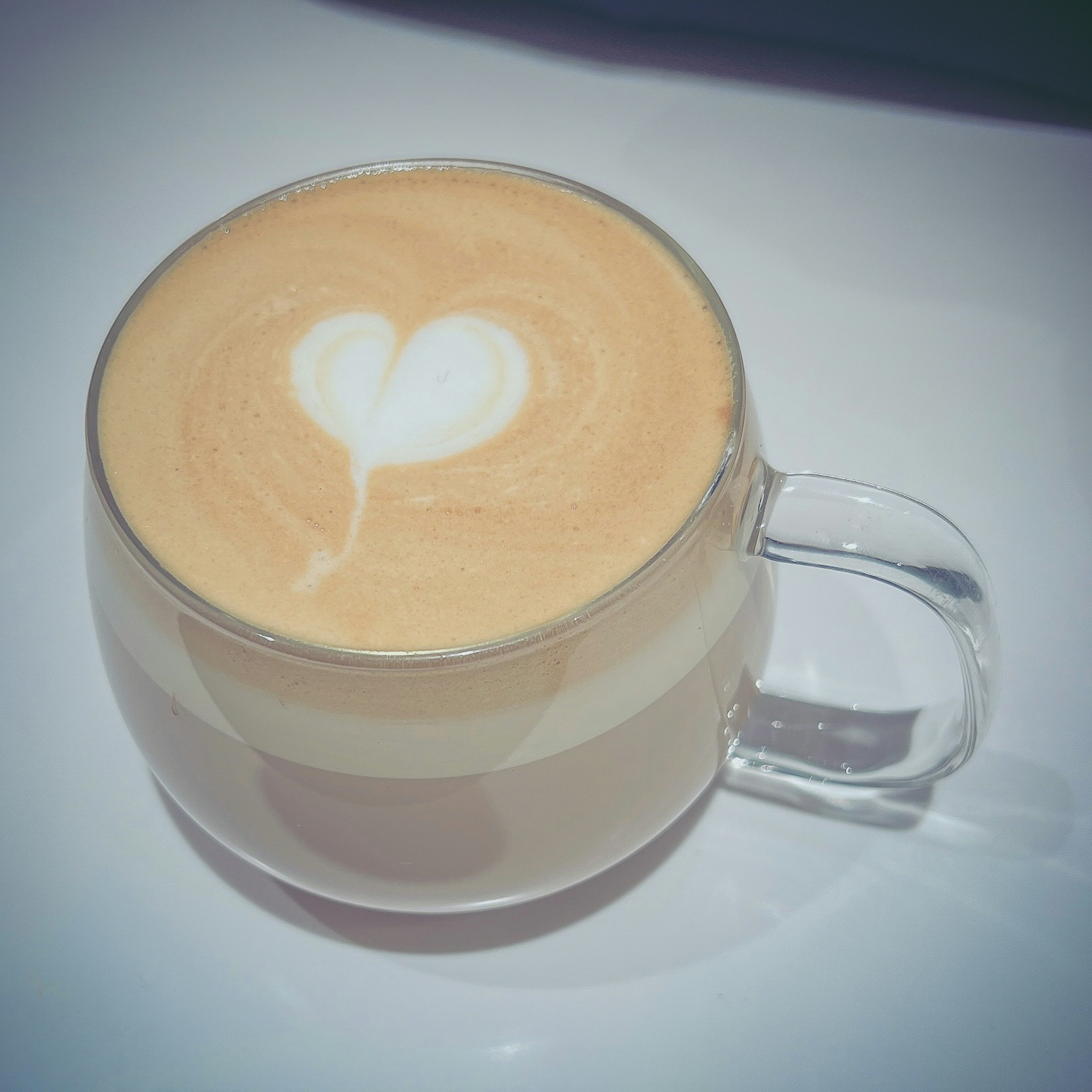 Latte art heart in a clear glass cup